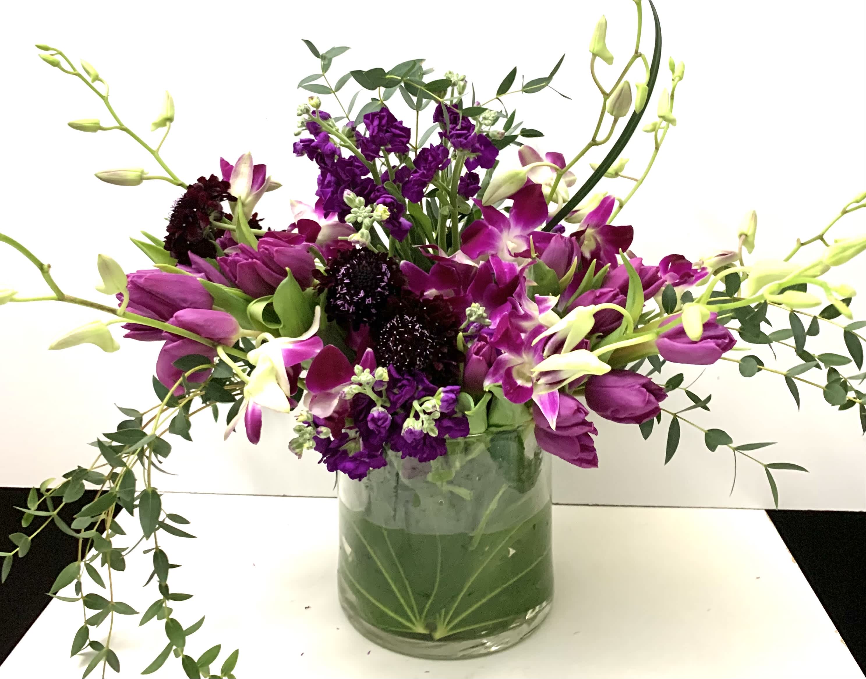 Purple tulips and orchids in a glass vase