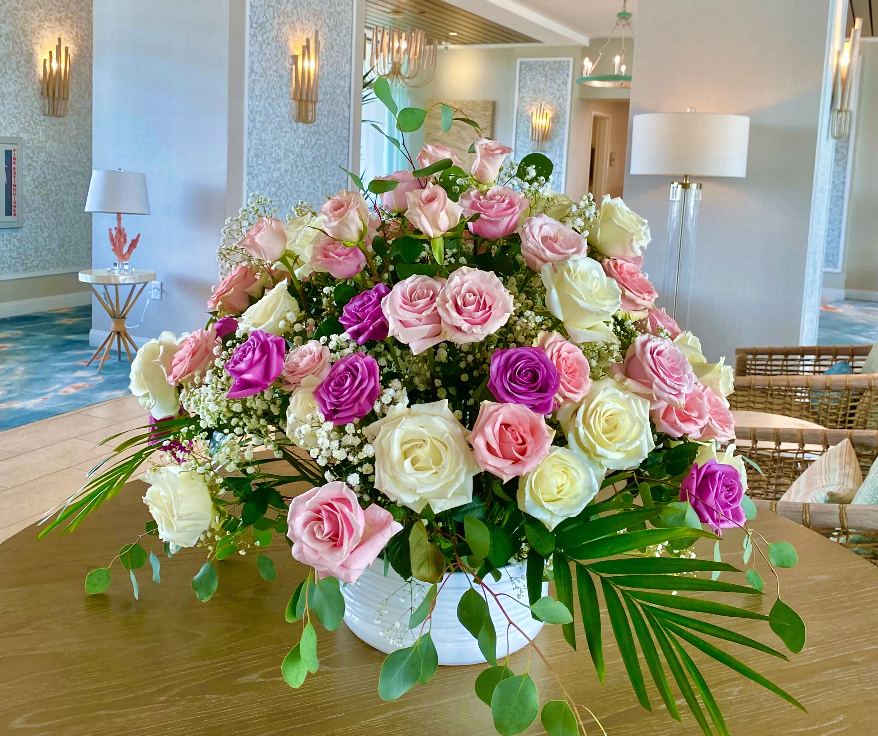 Large arrangement of pink, white, and purple roses in a white vase