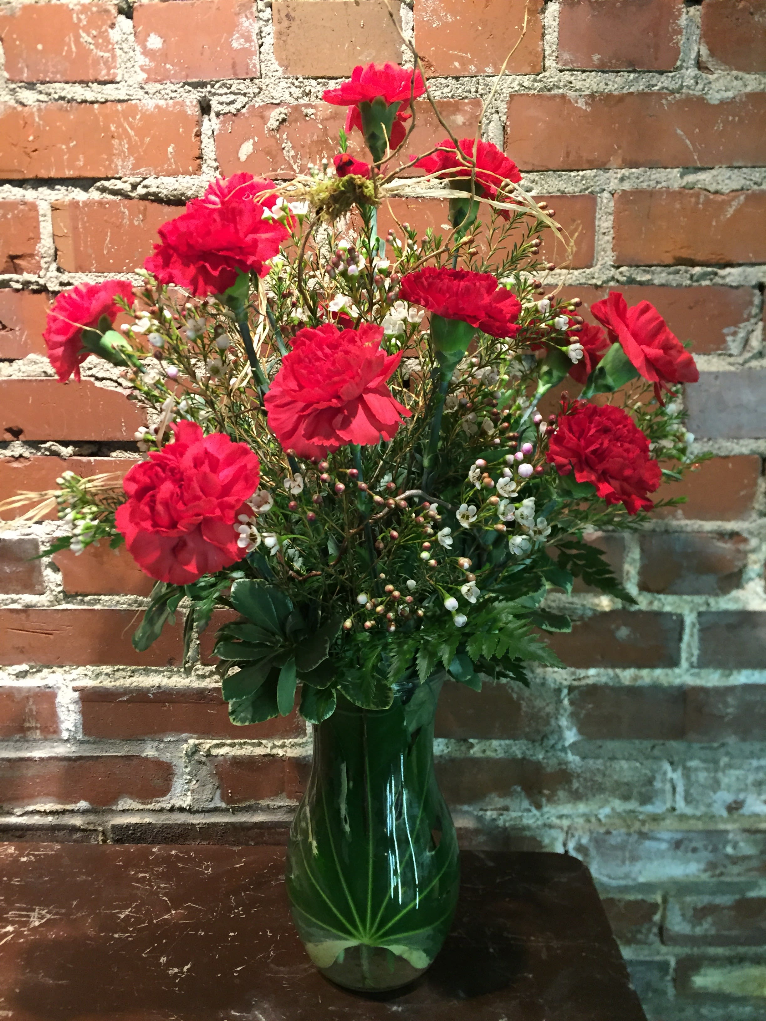 Red carnations in a green glass vase