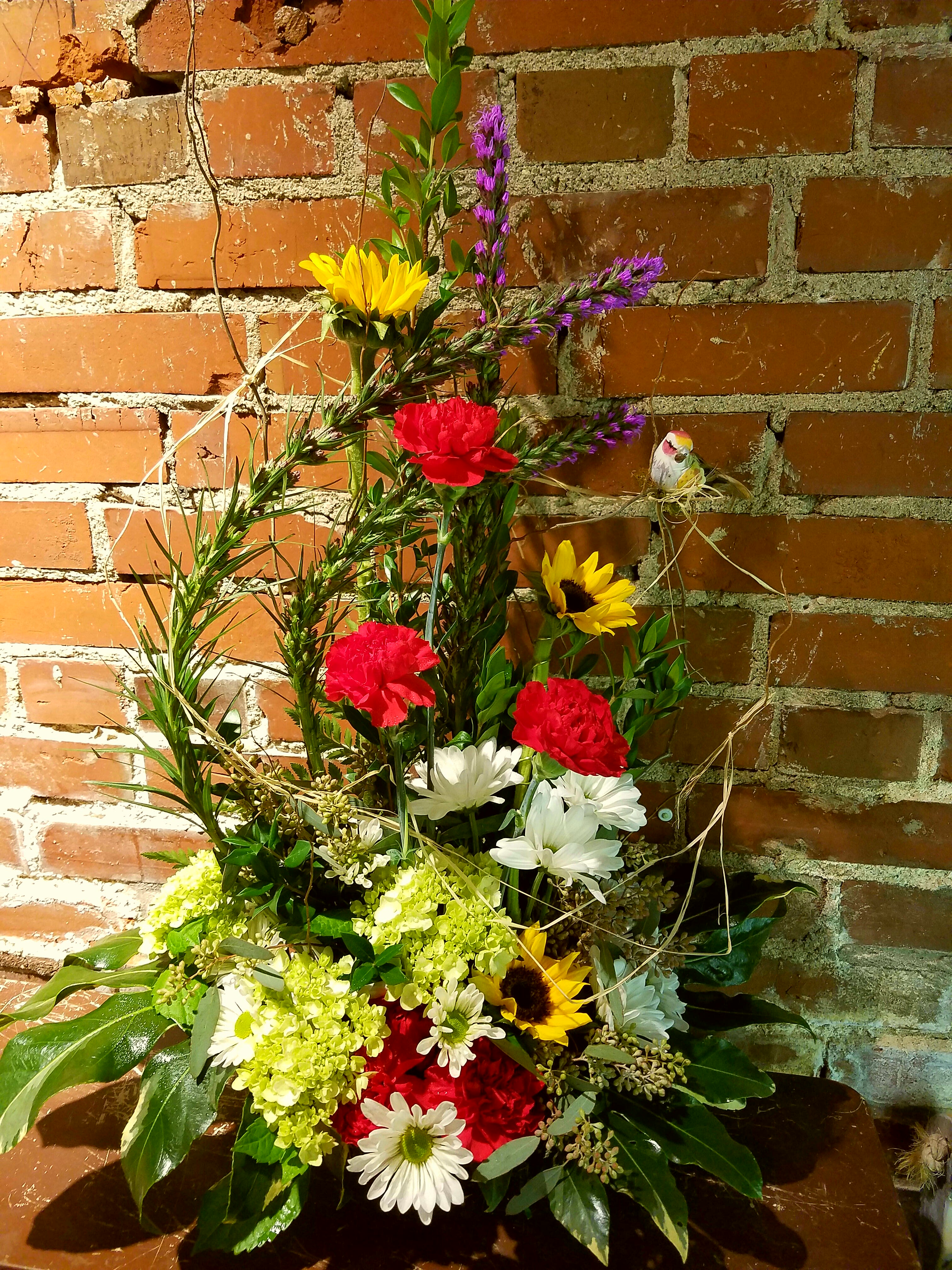 Tall mixed bouquet with sunflowers, carnations, and daisies
