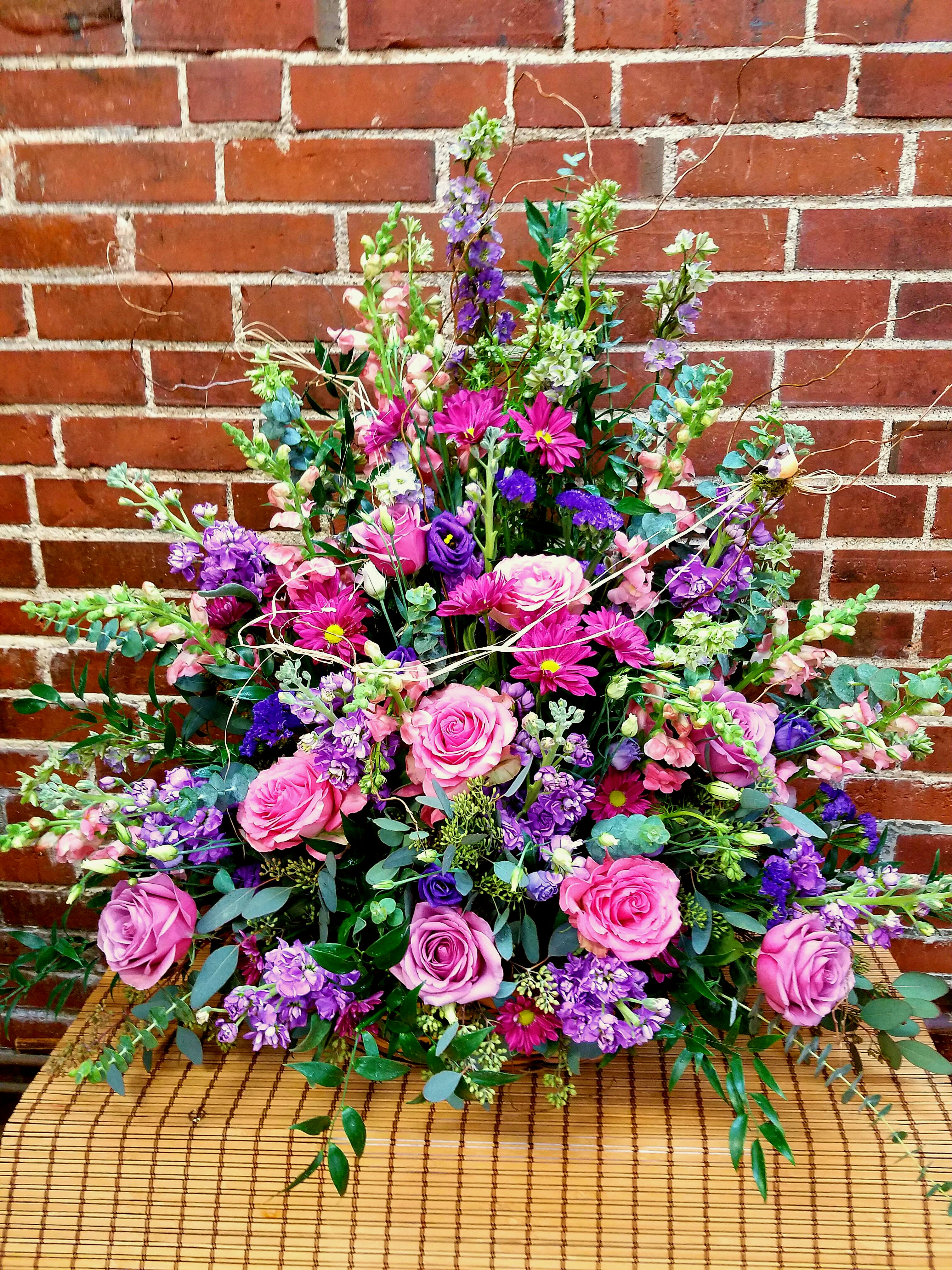 Large bouquet of pink and purple flowers arranged against a brick wall