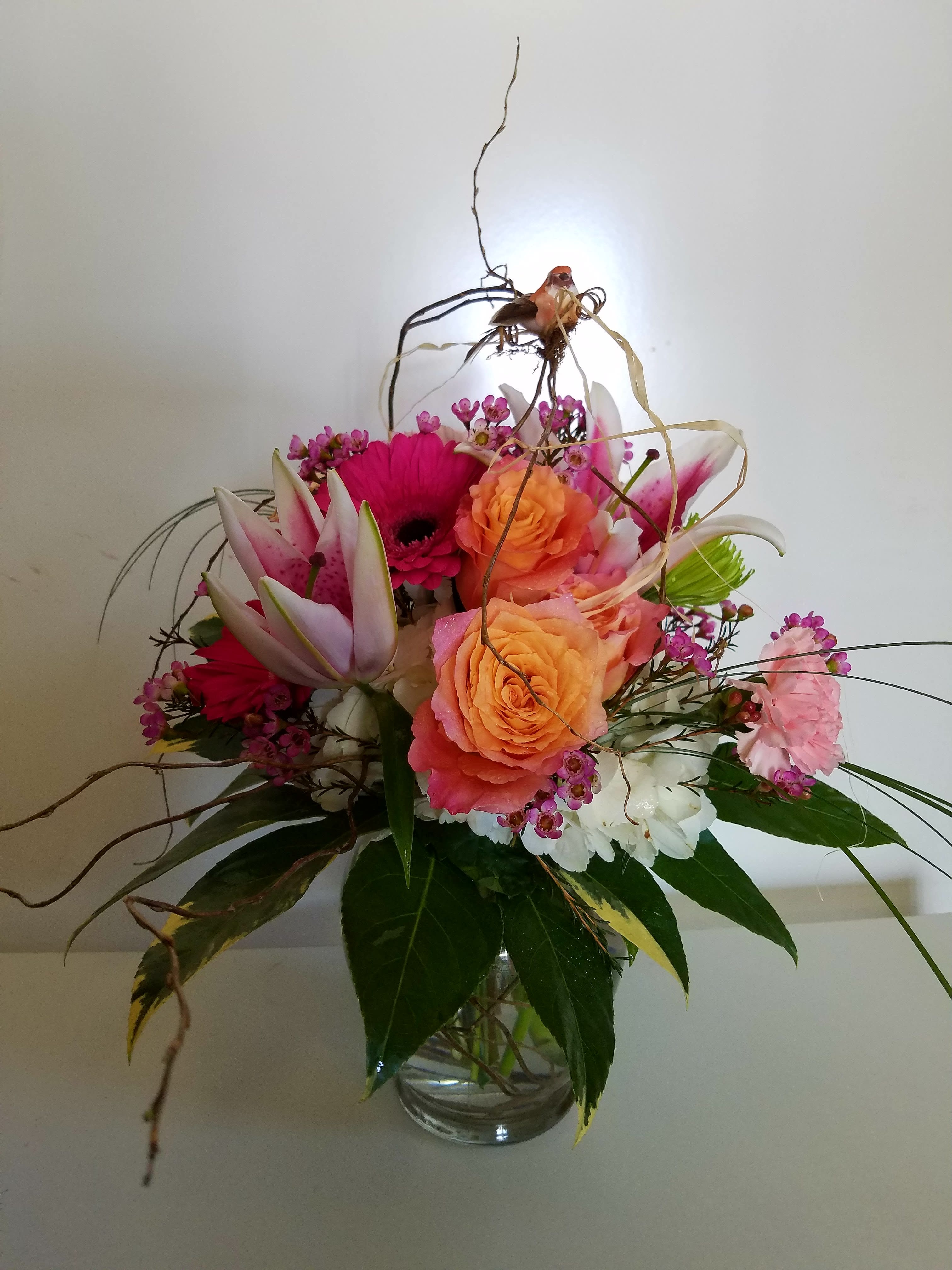Mixed bouquet of pink and orange flowers in a glass vase