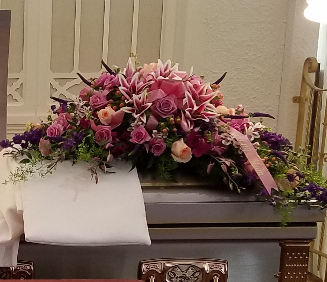 Large pink and purple floral casket spray with roses and lilies