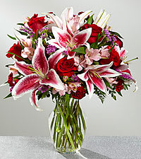 Bouquet of red roses and pink lilies in a clear glass vase