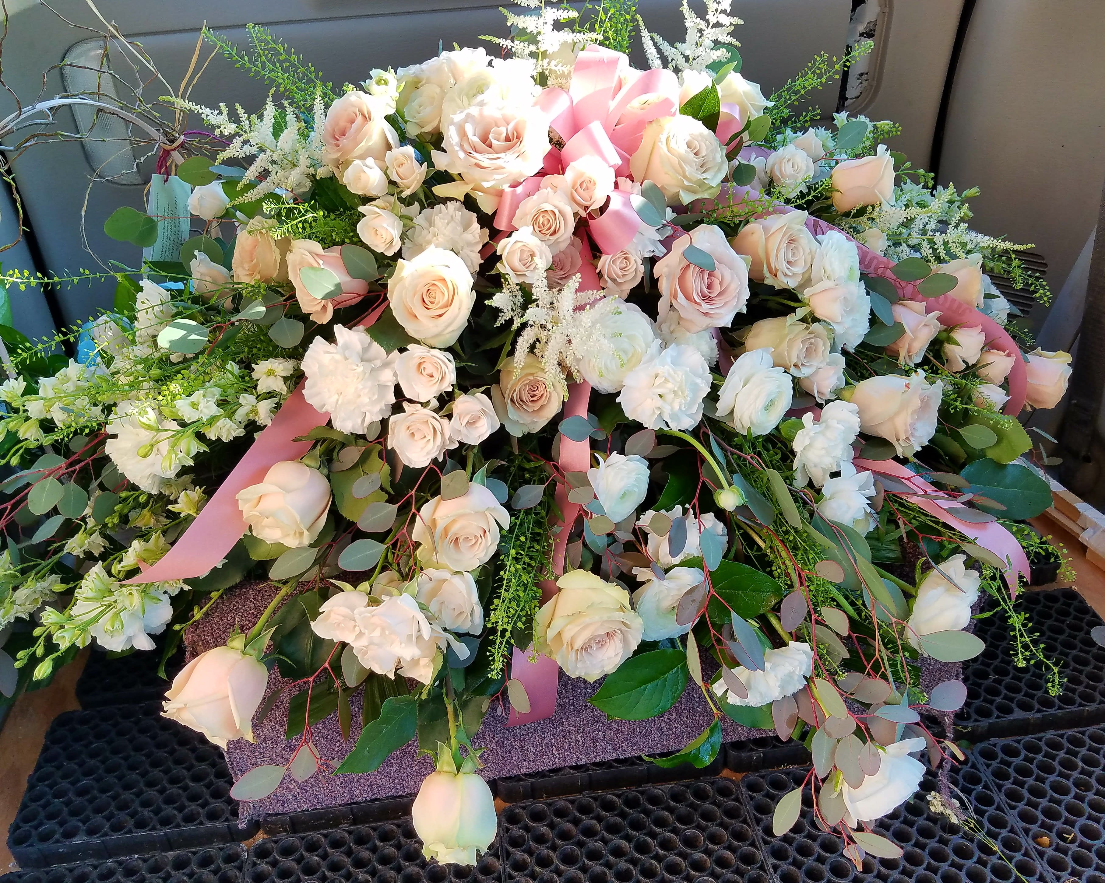 Large arrangement of pale pink and white roses with ribbon accents