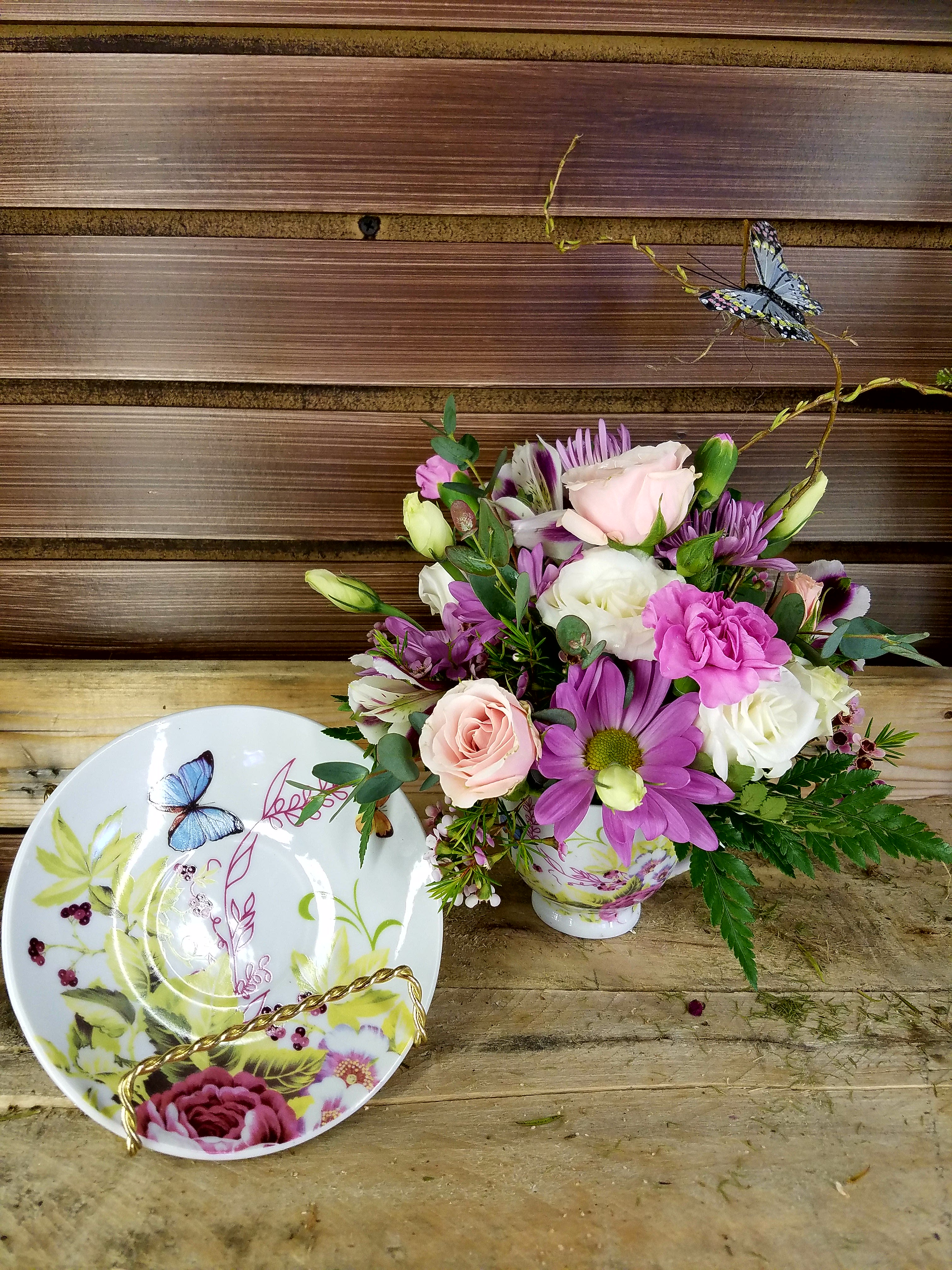 Bouquet of pink, white, and purple flowers in a decorative teacup vase