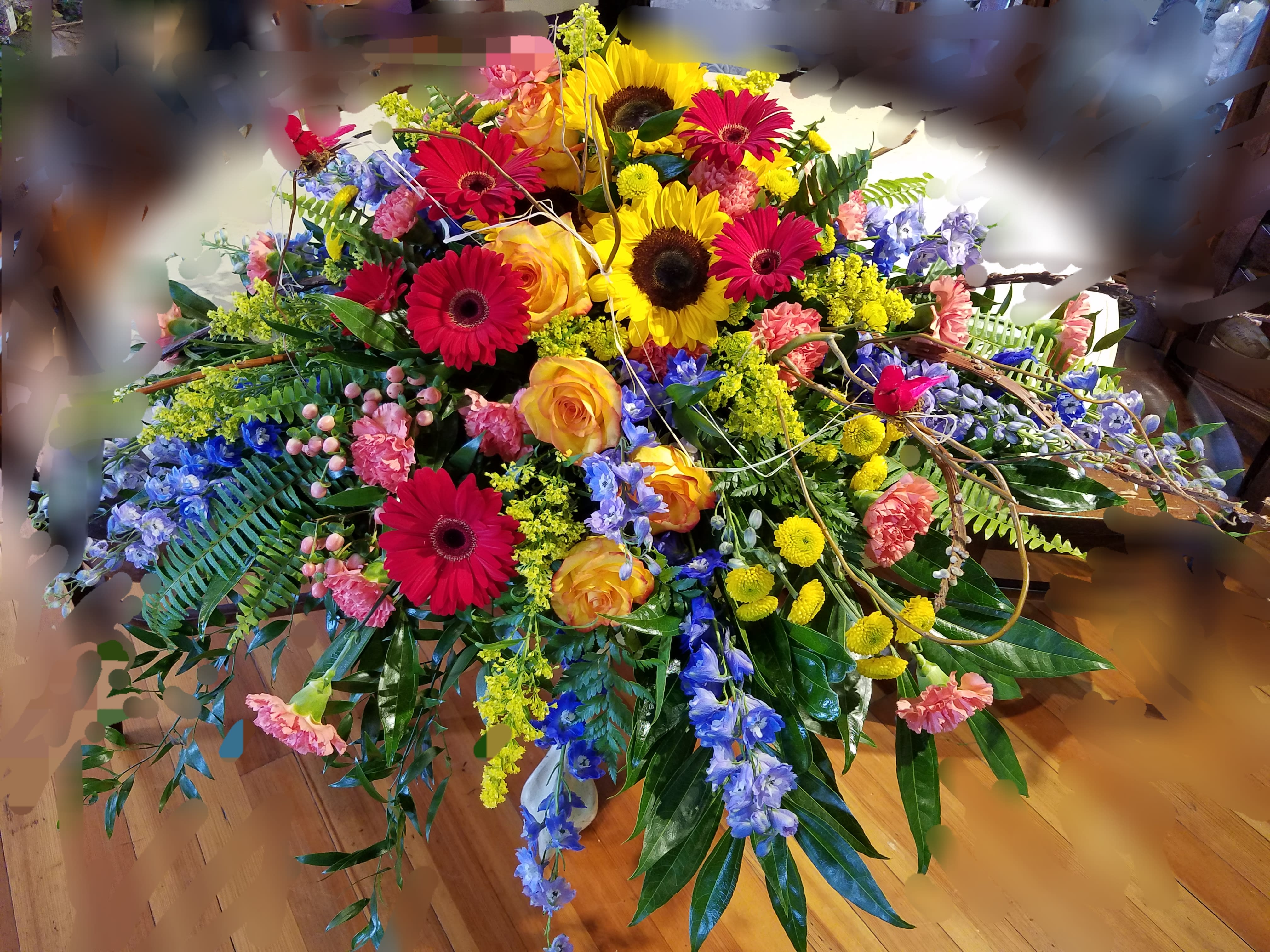 Large colorful floral arrangement with gerbera daisies, roses, and sunflowers