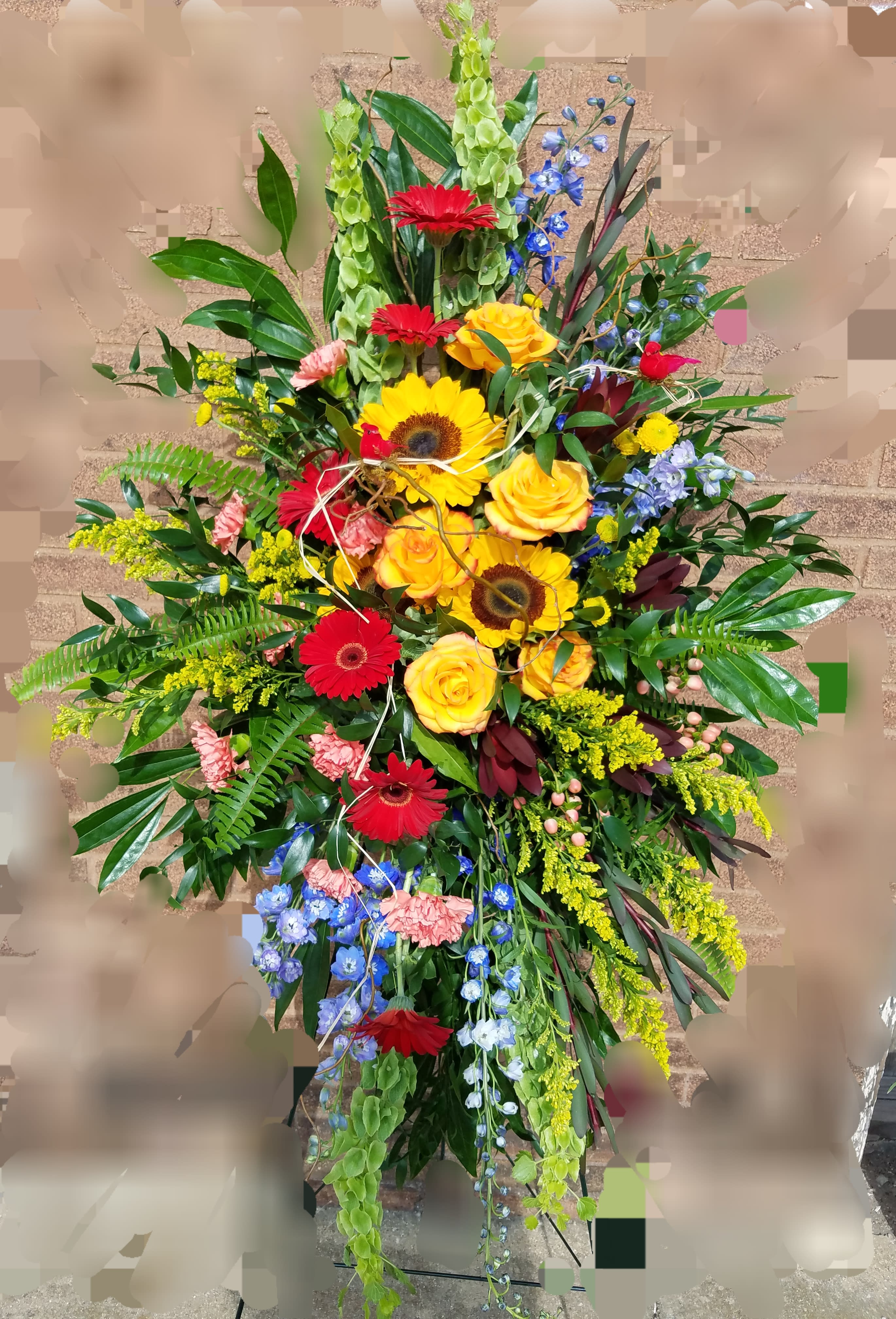 Tall mixed floral spray with red gerberas, yellow roses, and blue flowers