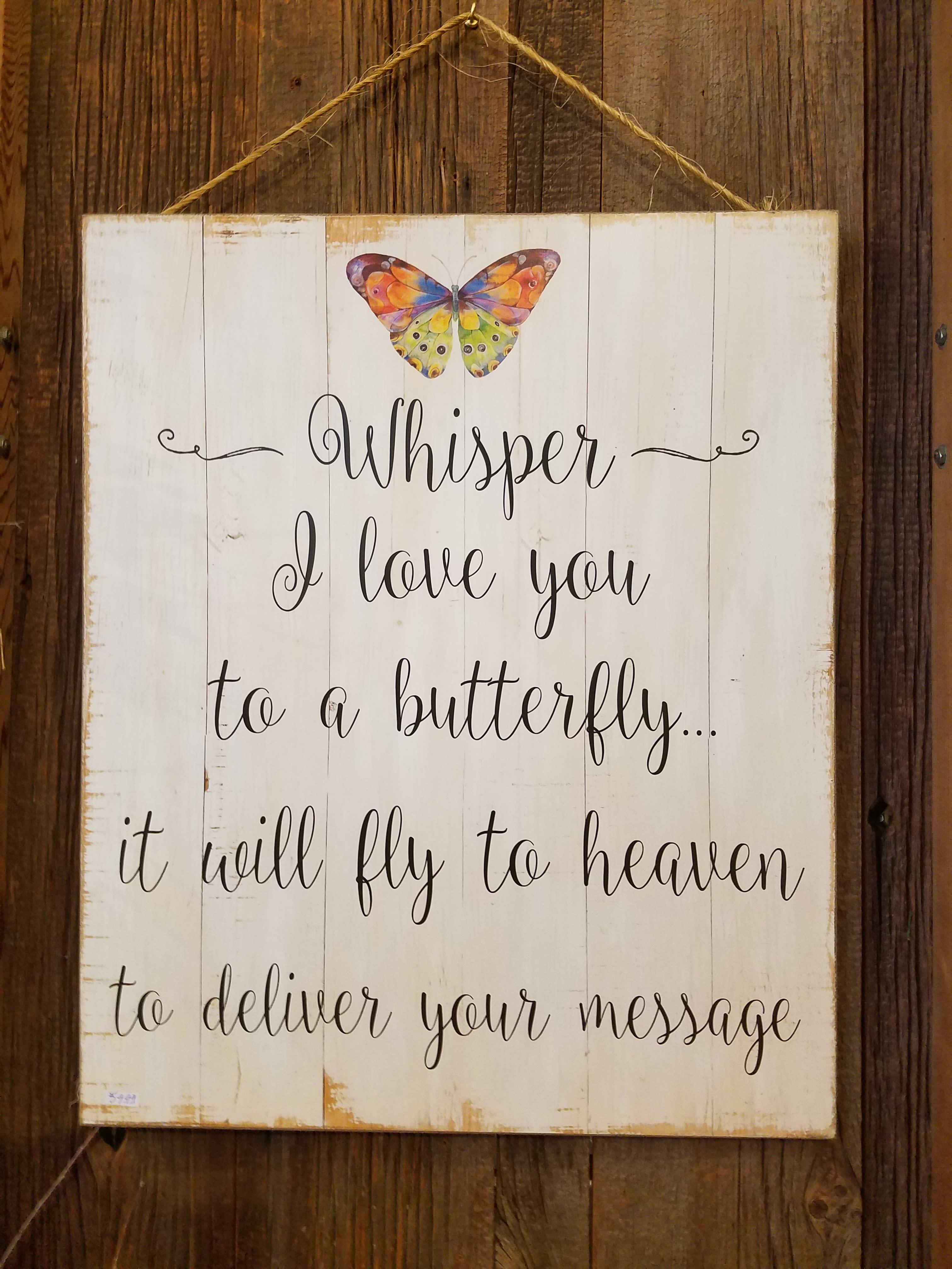 Wooden memorial sign with a colorful butterfly and the words "Whisper I love you"