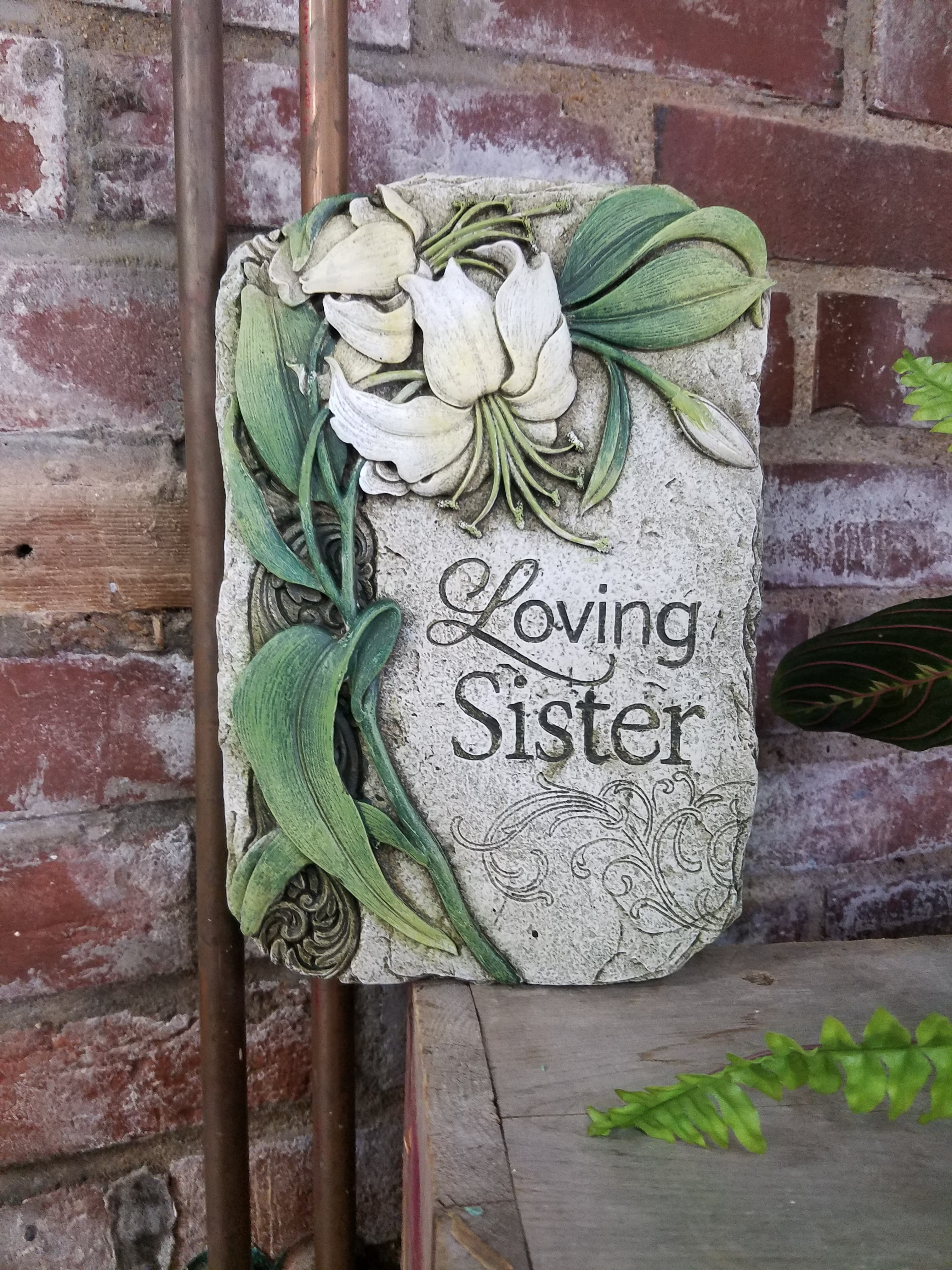 Decorative stone plaque with white lilies and the words Loving Sister