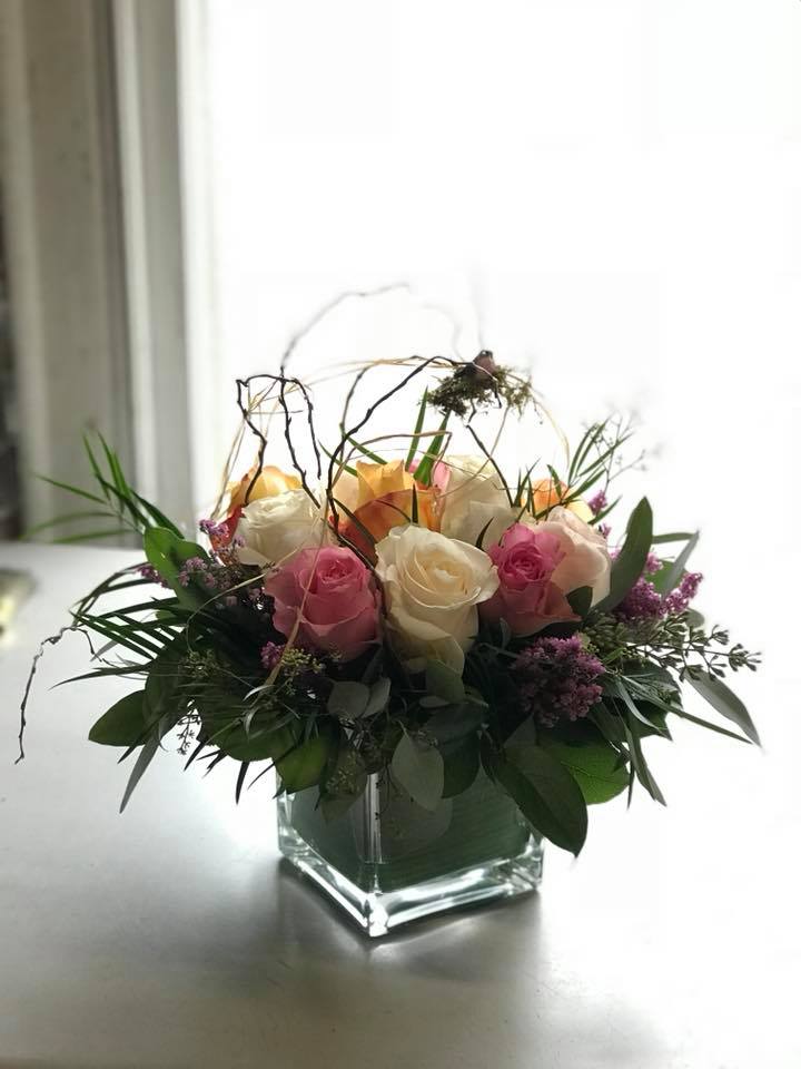 Pink and white roses arranged in a square glass vase
