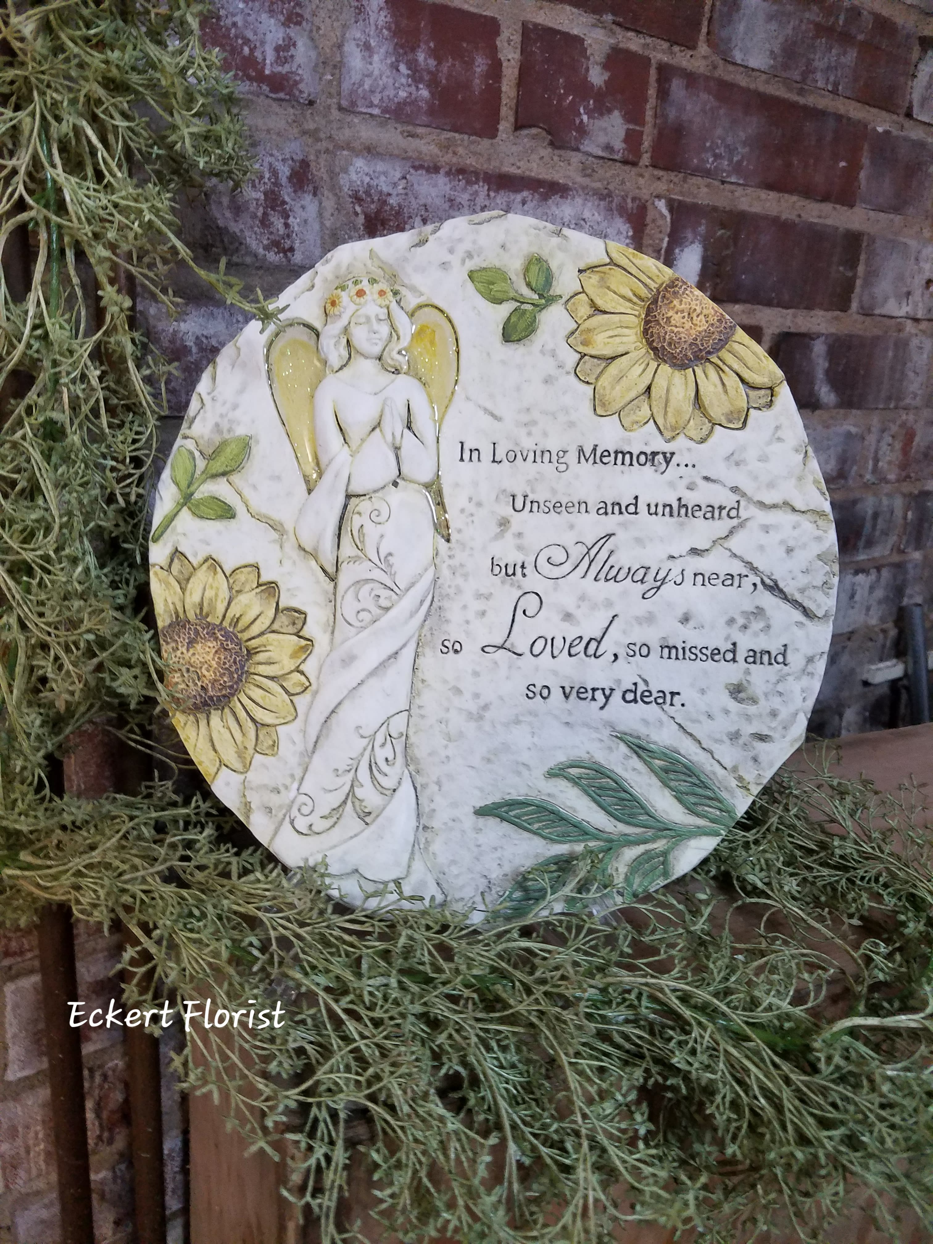 Round memorial plaque with an angel and sunflowers
