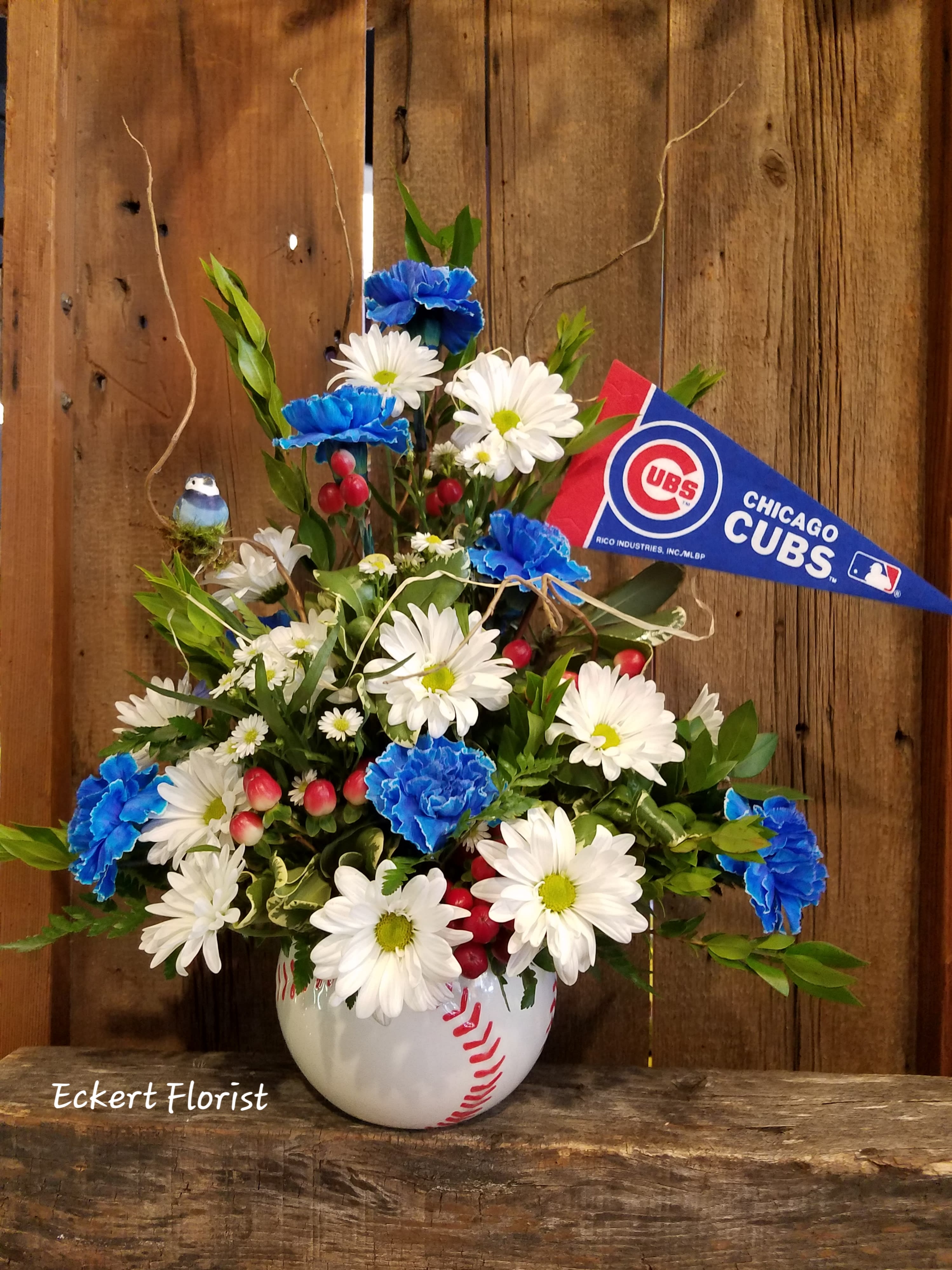 Baseball-themed flower arrangement in a baseball vase with a Cubs pennant