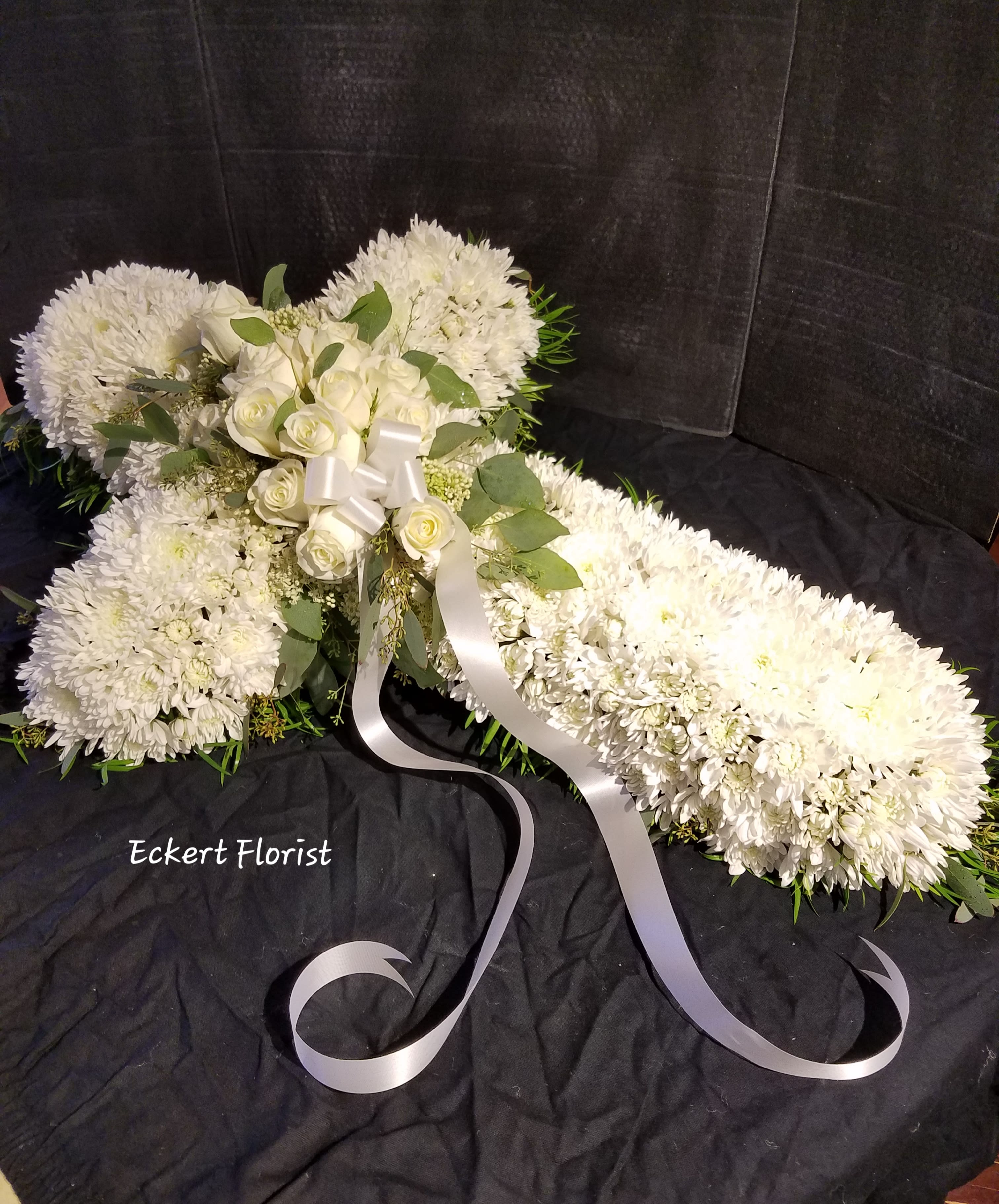 White floral spray with roses and chrysanthemums tied with a white ribbon