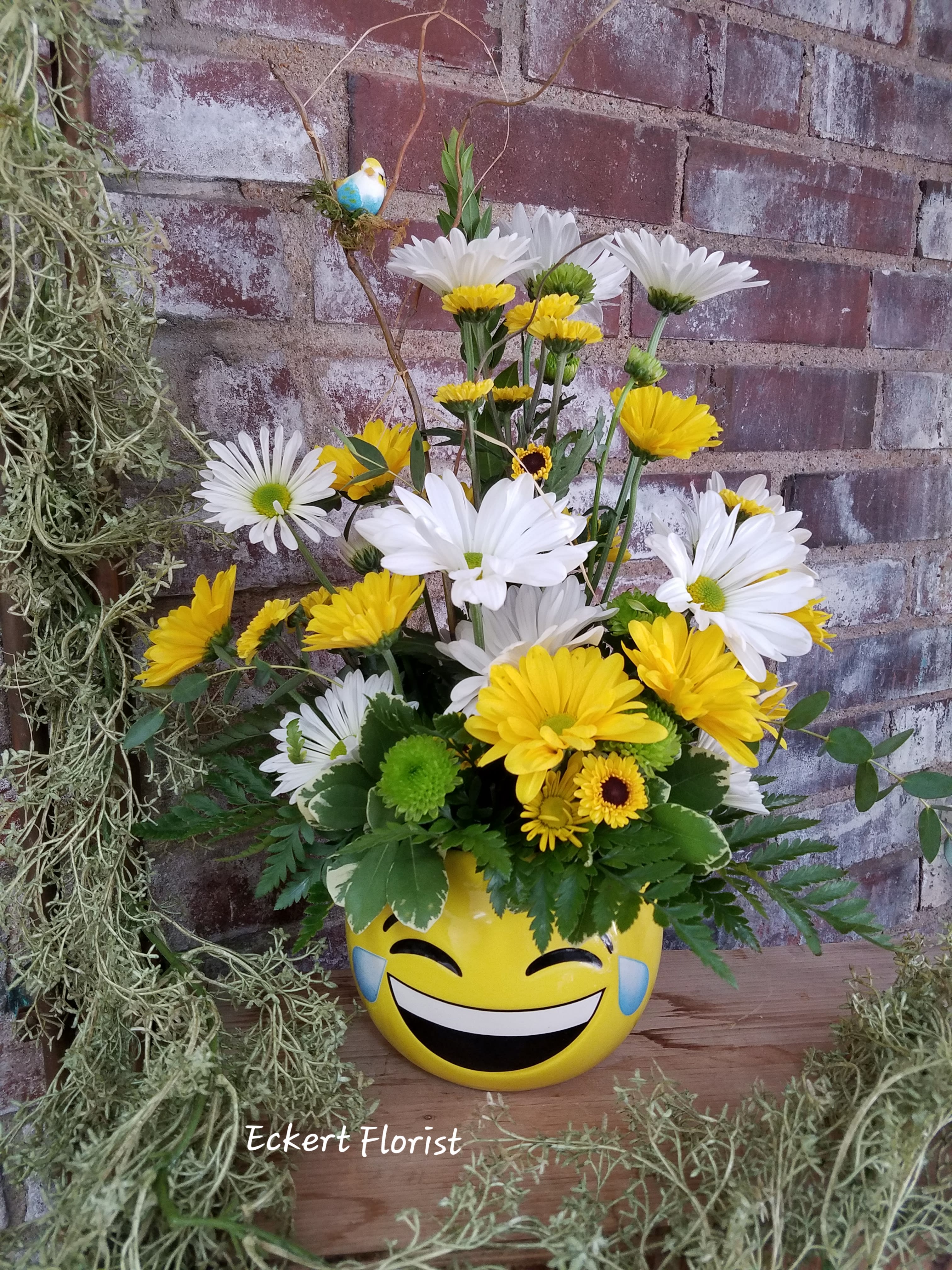 Yellow and white daisy bouquet in a smiley-face pot