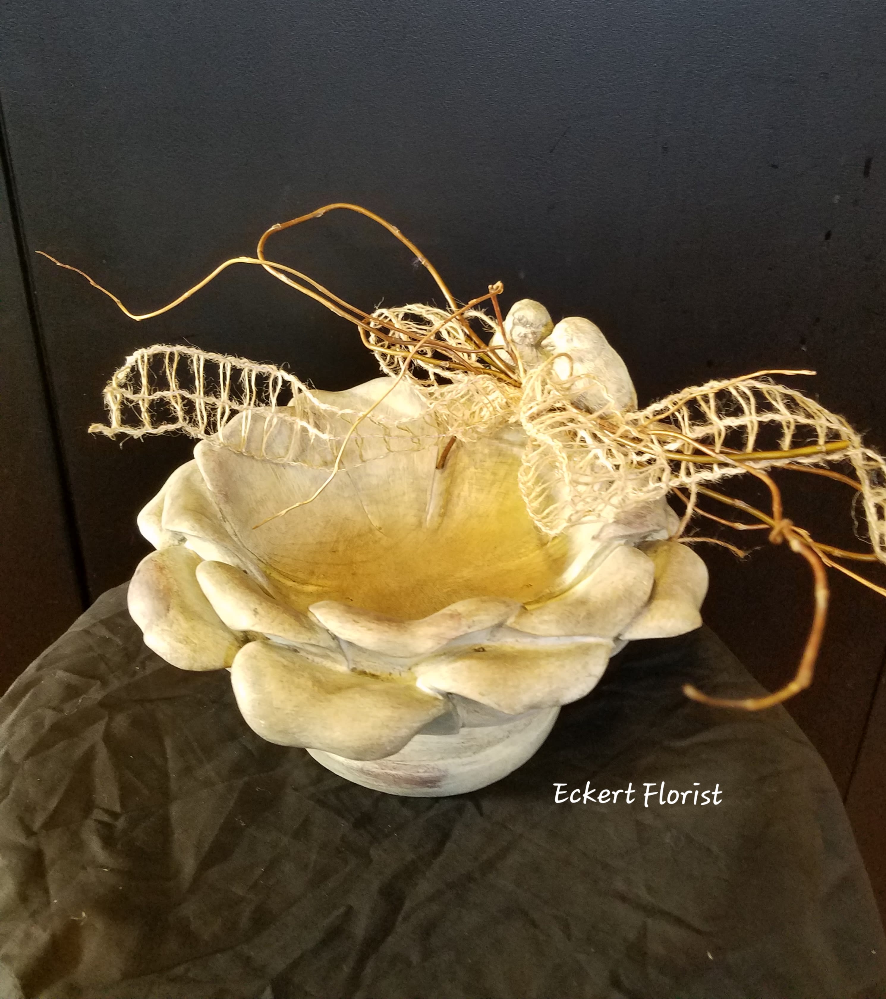 Cream-colored decorative bowl with dried twigs and mesh accents