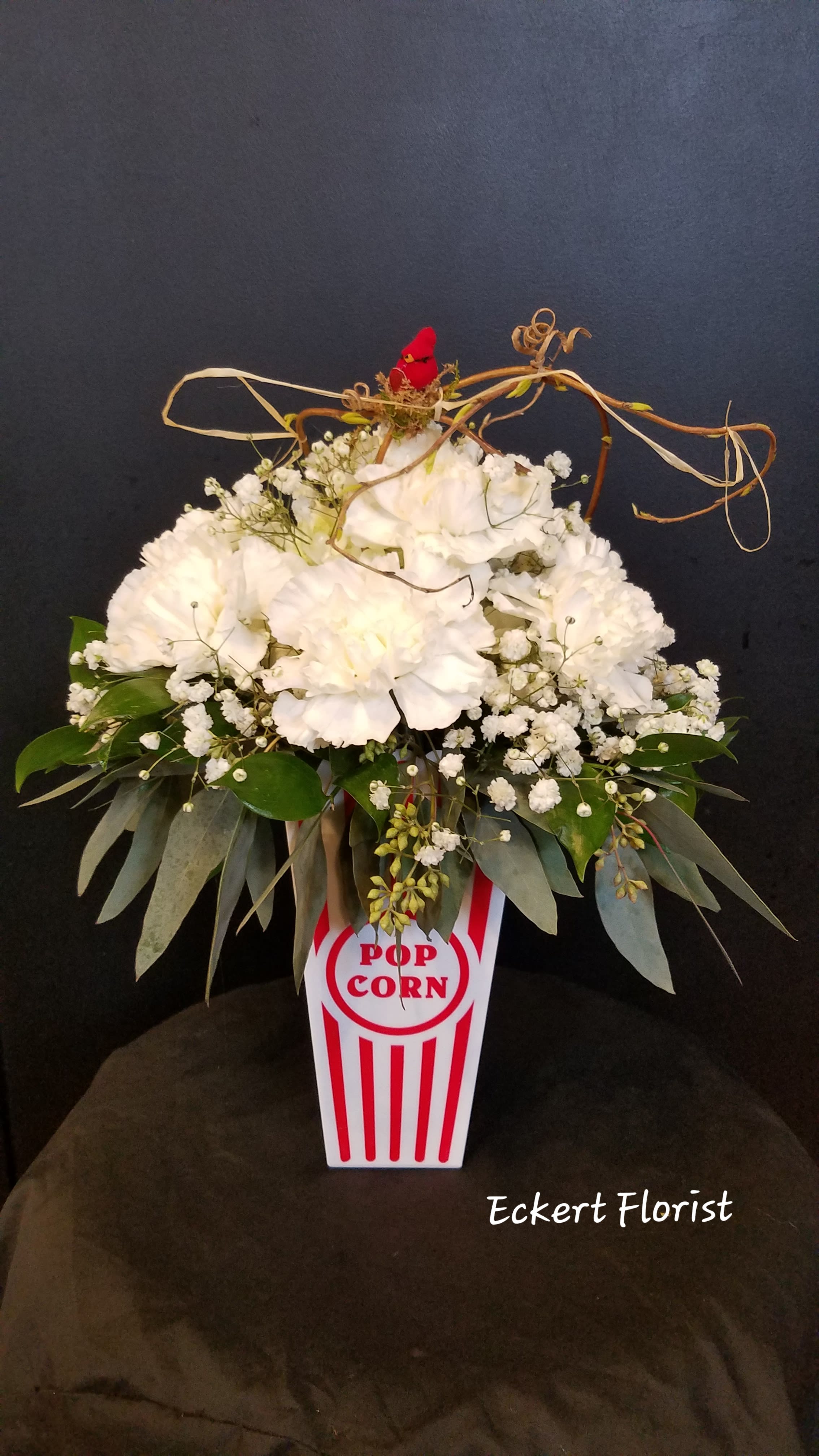 White floral arrangement in a popcorn box-shaped container