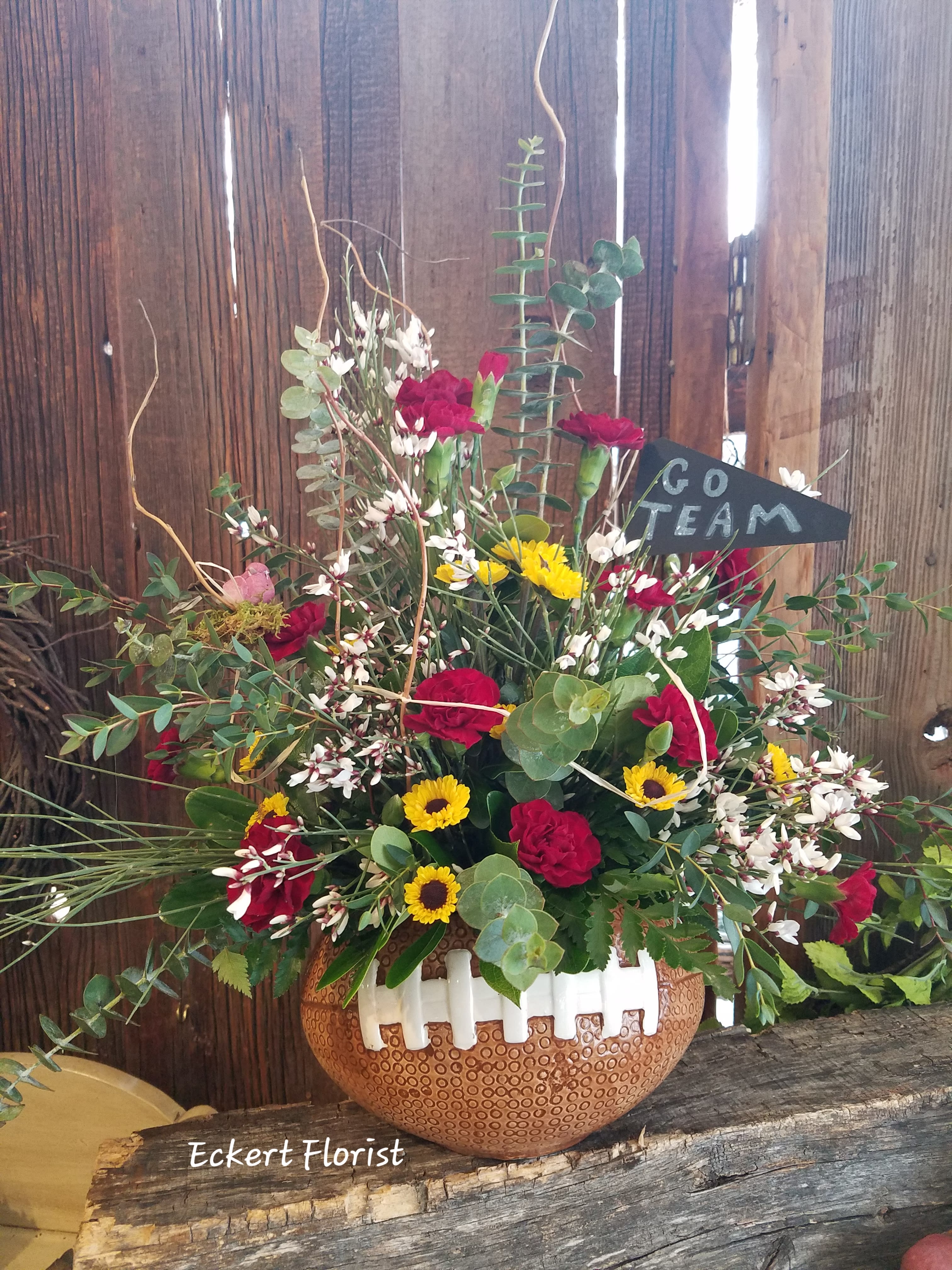 Mixed bouquet in a football-shaped vase with a "Go Team" sign