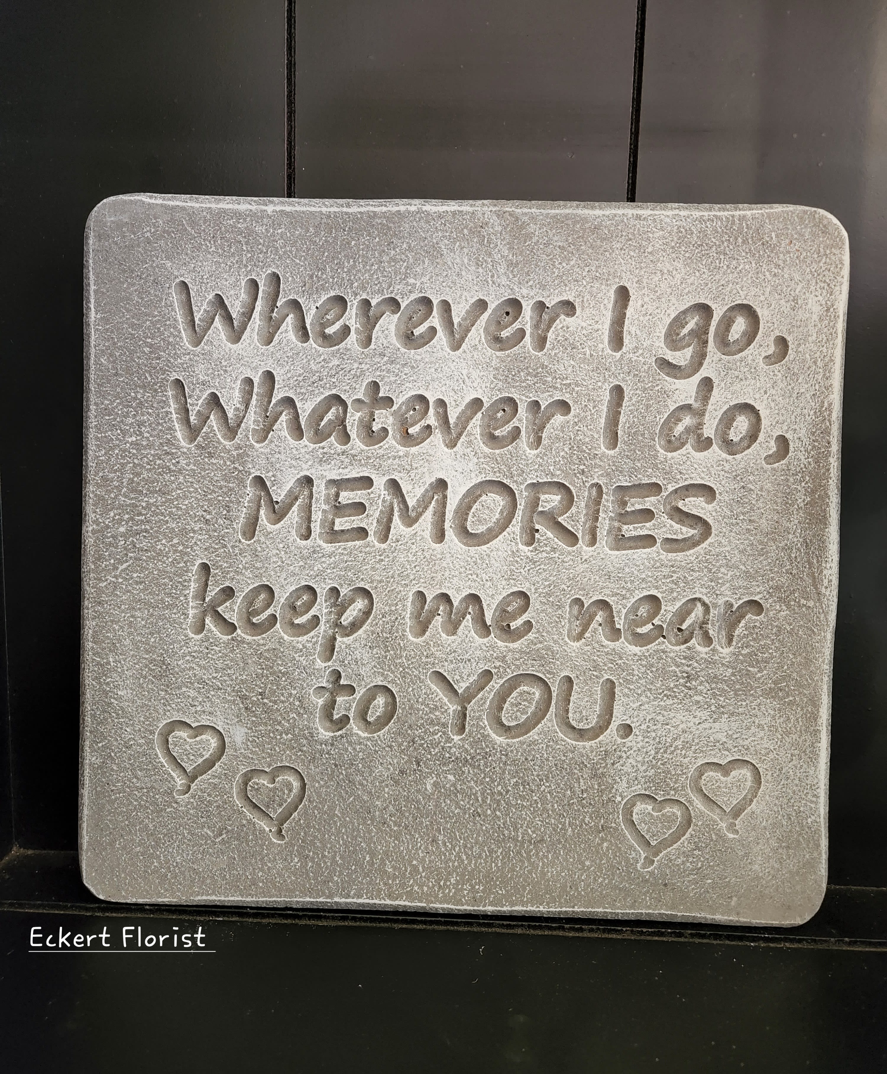 Gray memorial plaque with engraved quote and small heart balloons