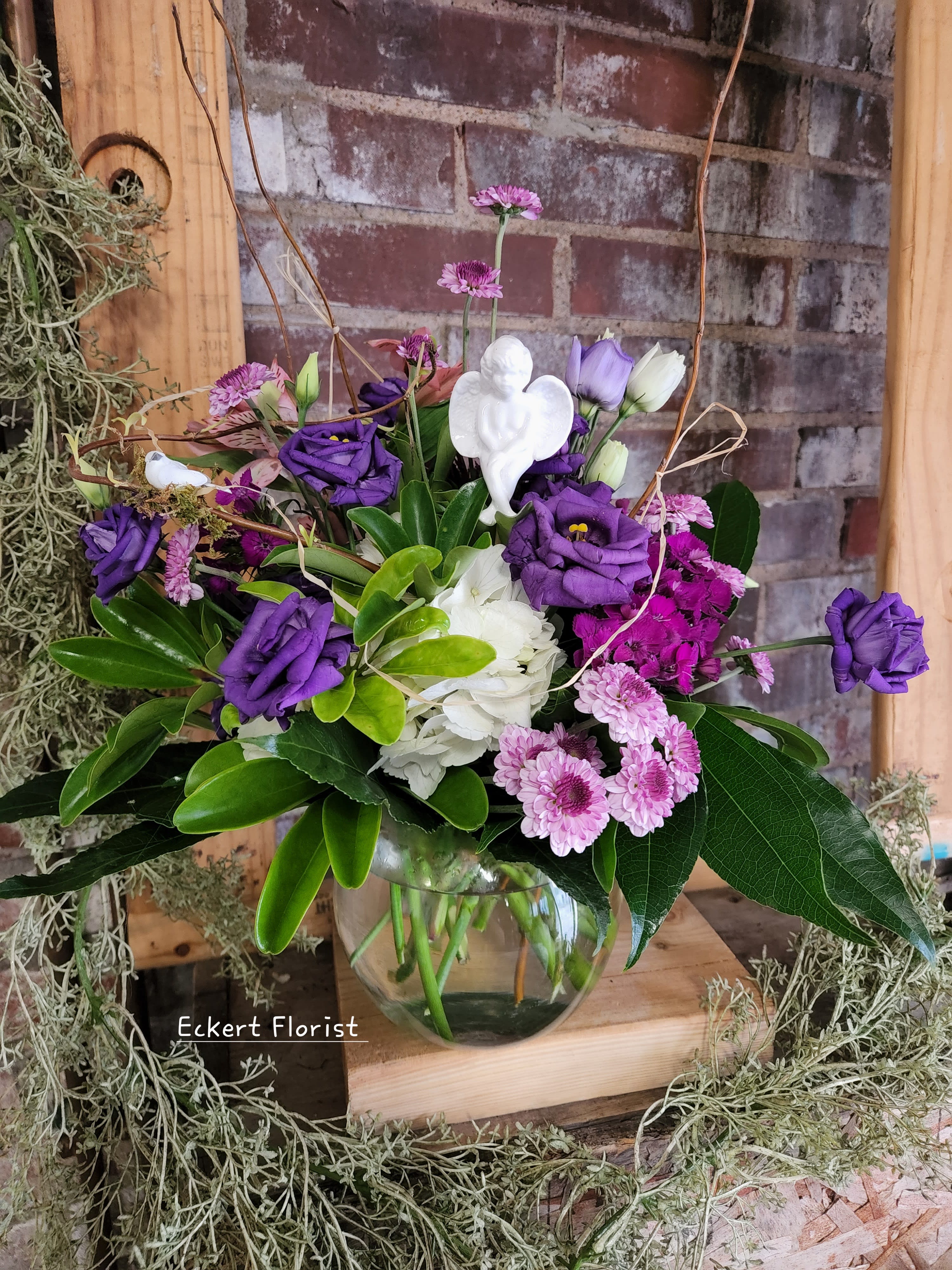 Purple and white flowers arranged in a clear glass vase