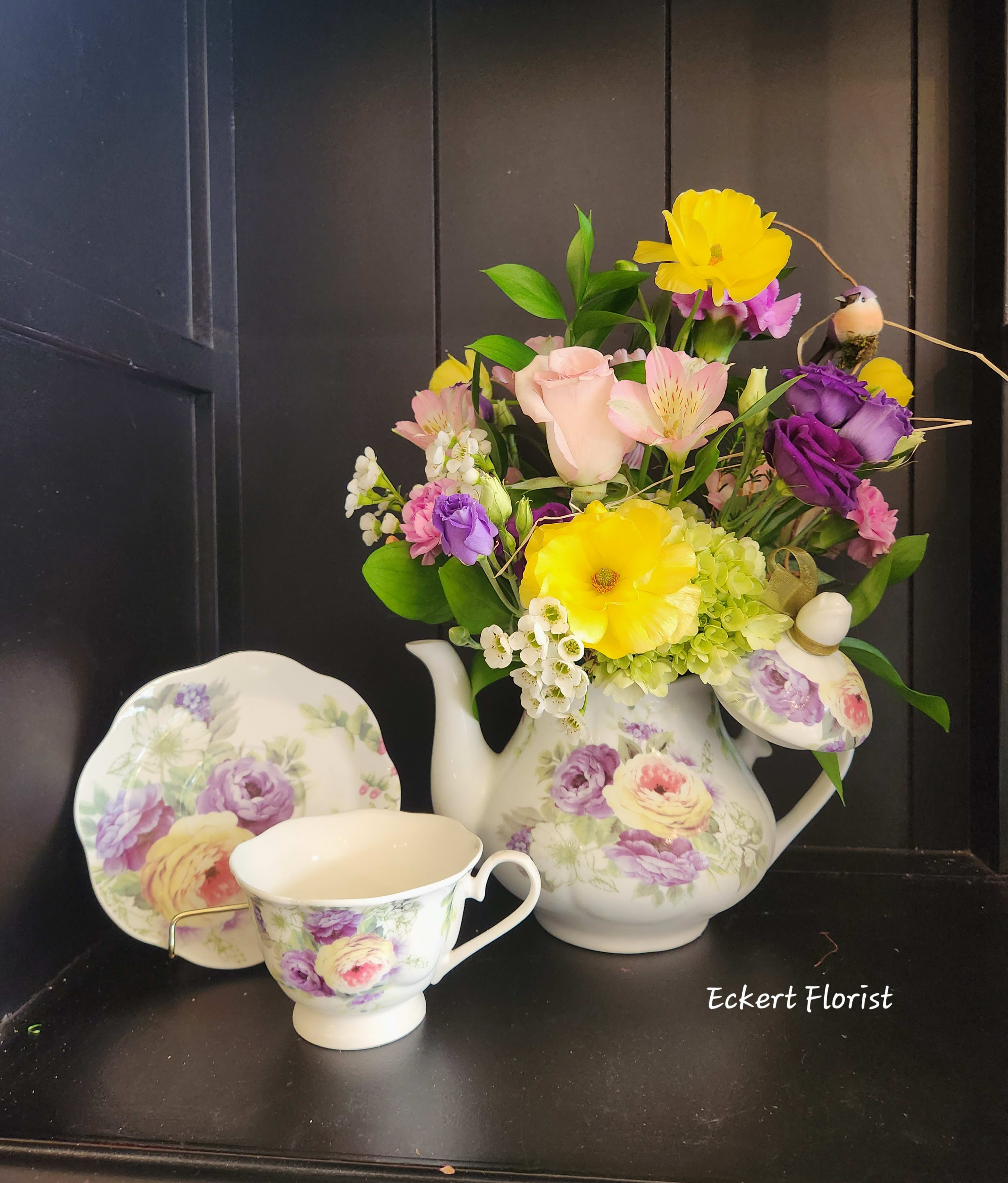 Floral arrangement in a floral teapot with matching teacup and saucer