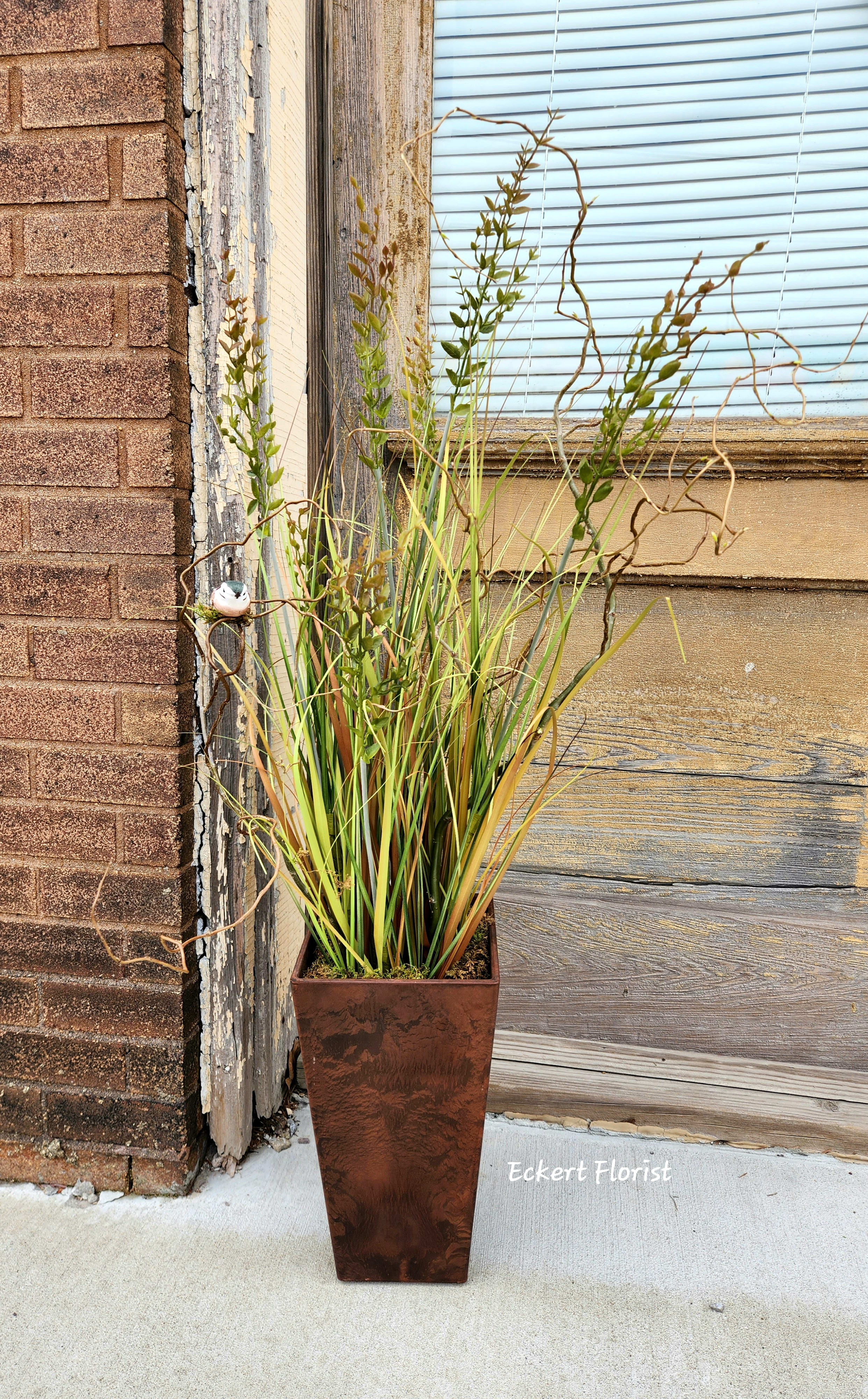 Tall potted arrangement of ornamental grasses in a copper planter