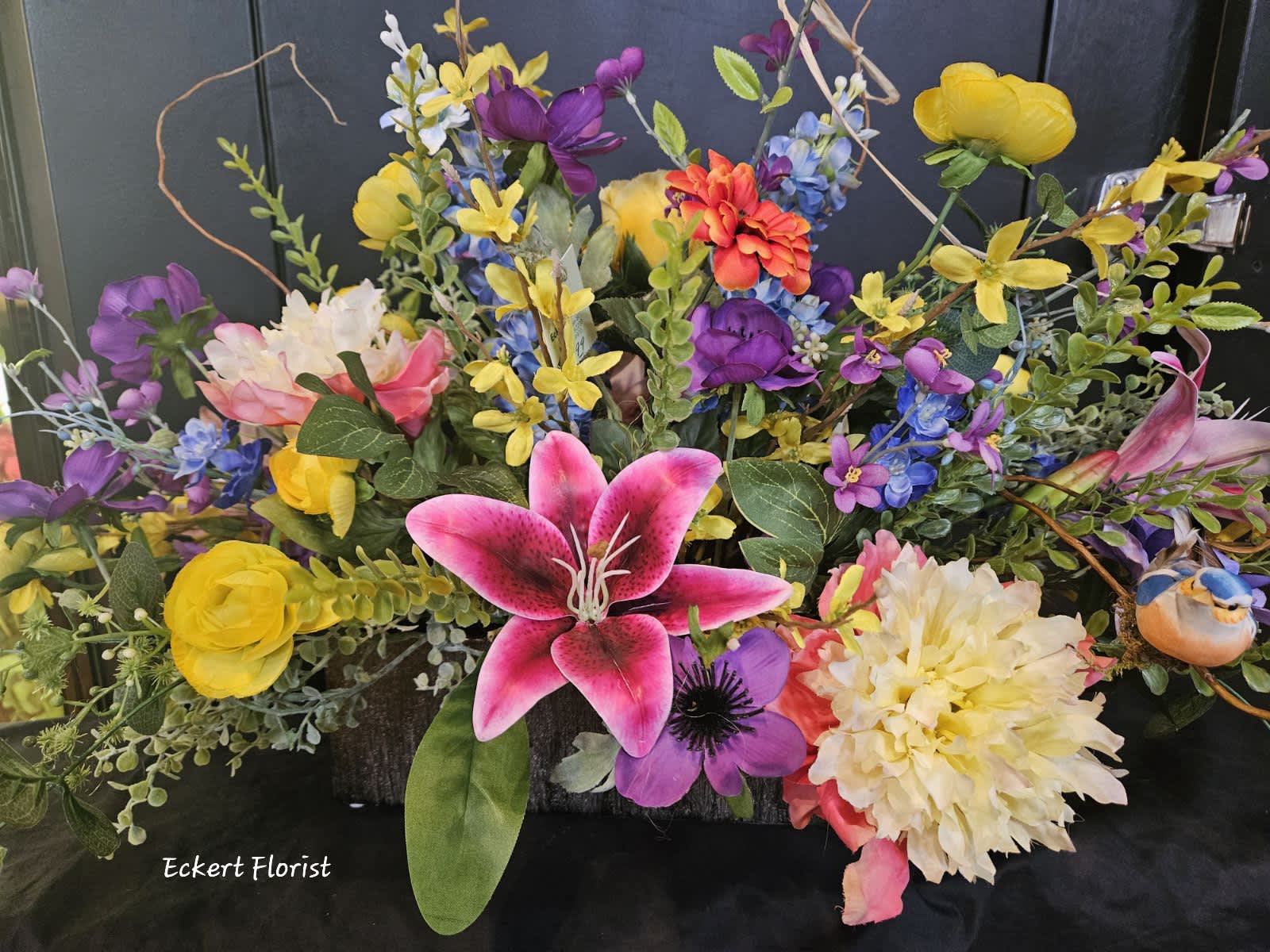 Colorful floral arrangement with lilies, daisies, and mixed blooms in a low container