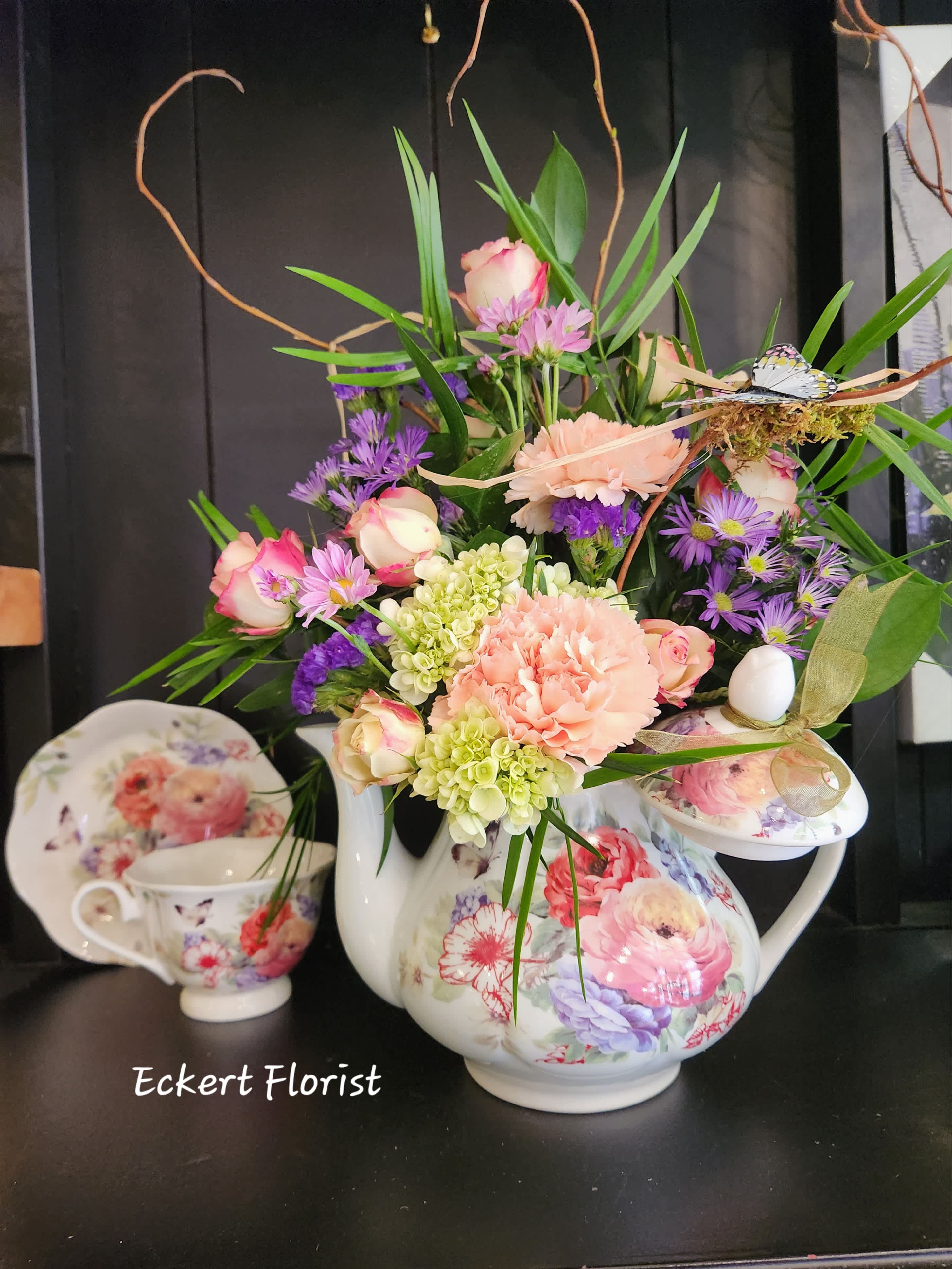 Floral arrangement in a floral teapot with pink, purple, and green blooms