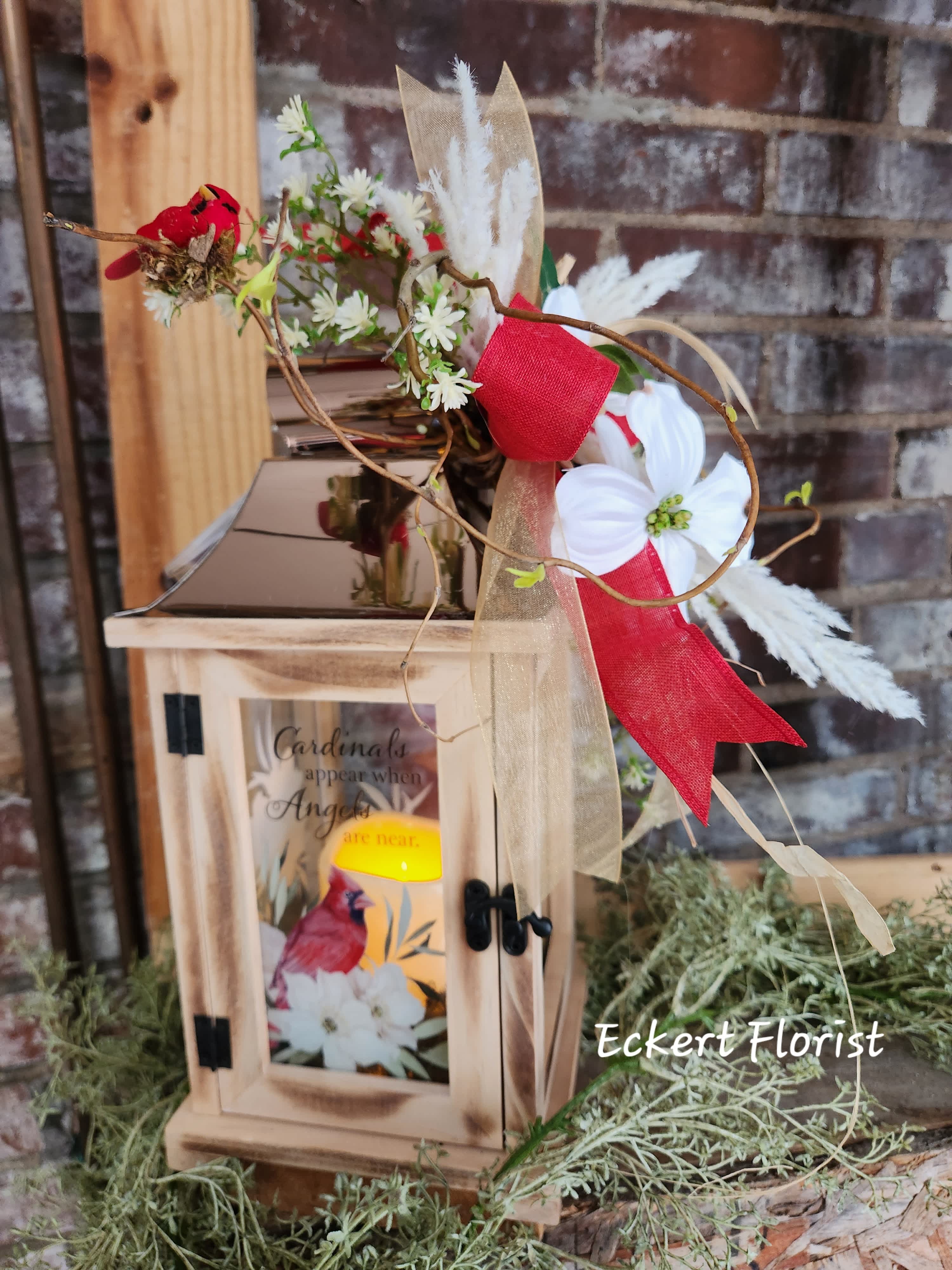 Wooden lantern with a floral spray and red ribbon accents
