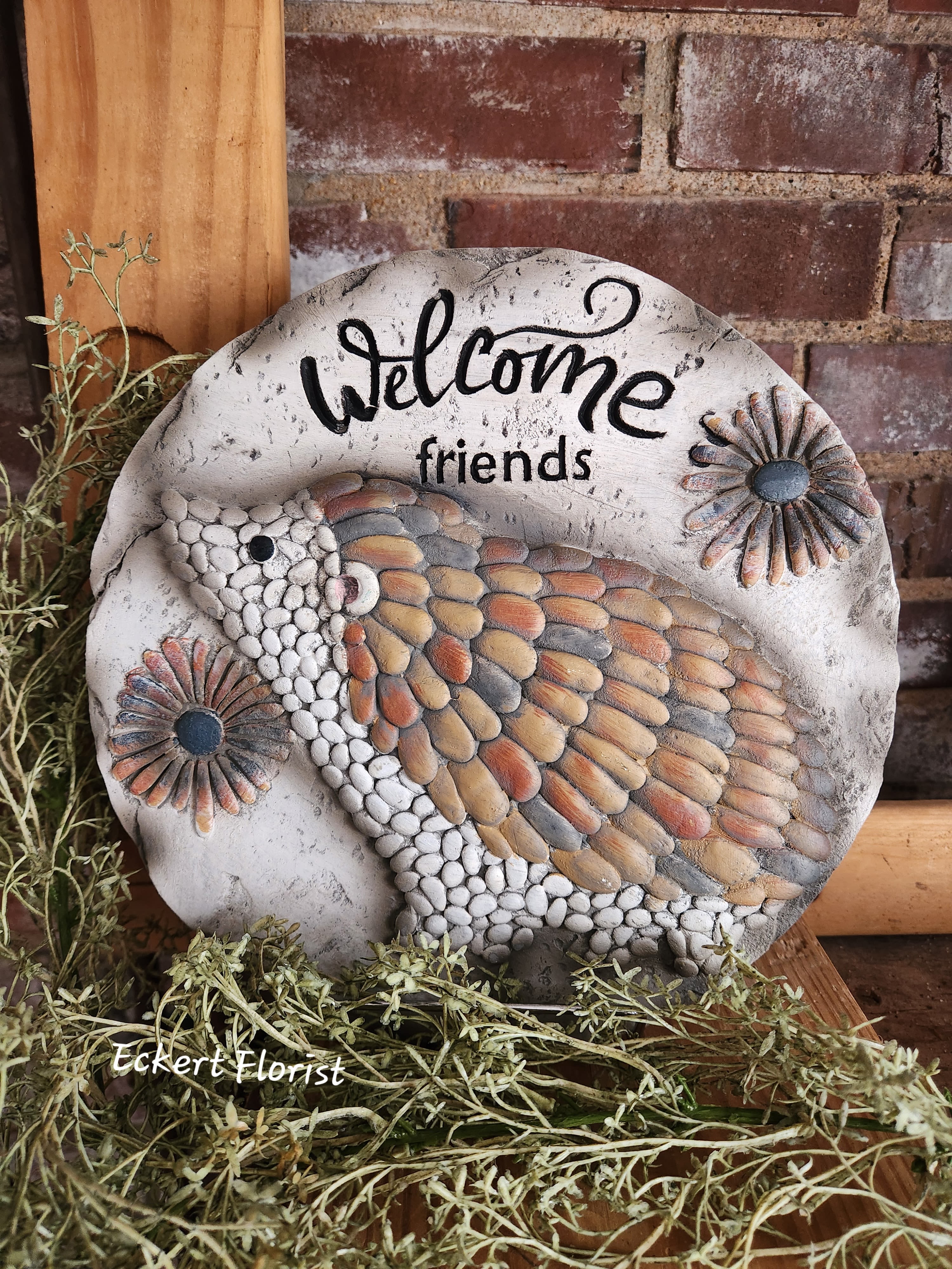 Round decorative stone plaque with a bird and "Welcome friends" text