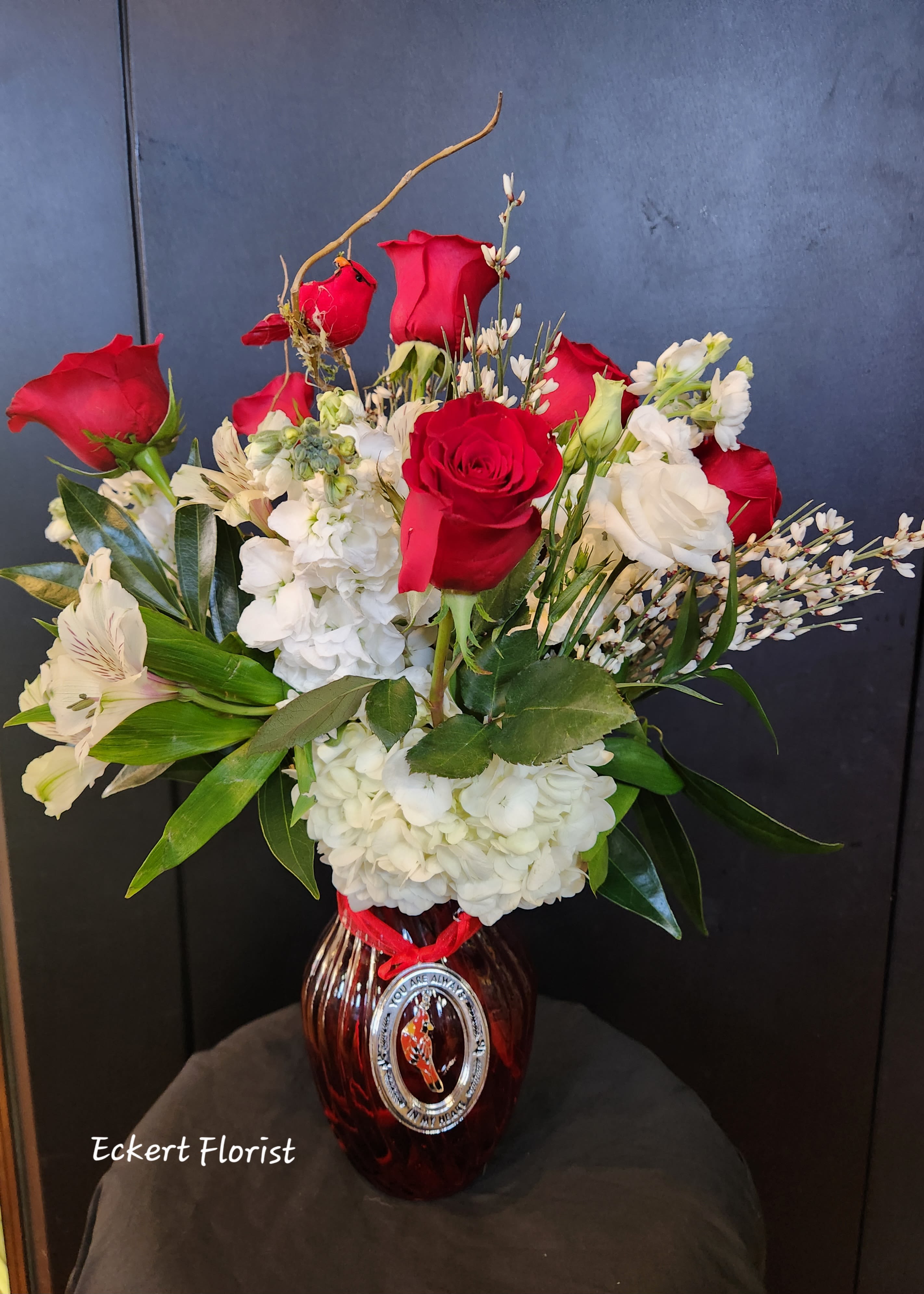 Red roses and white flowers arranged in a glass vase