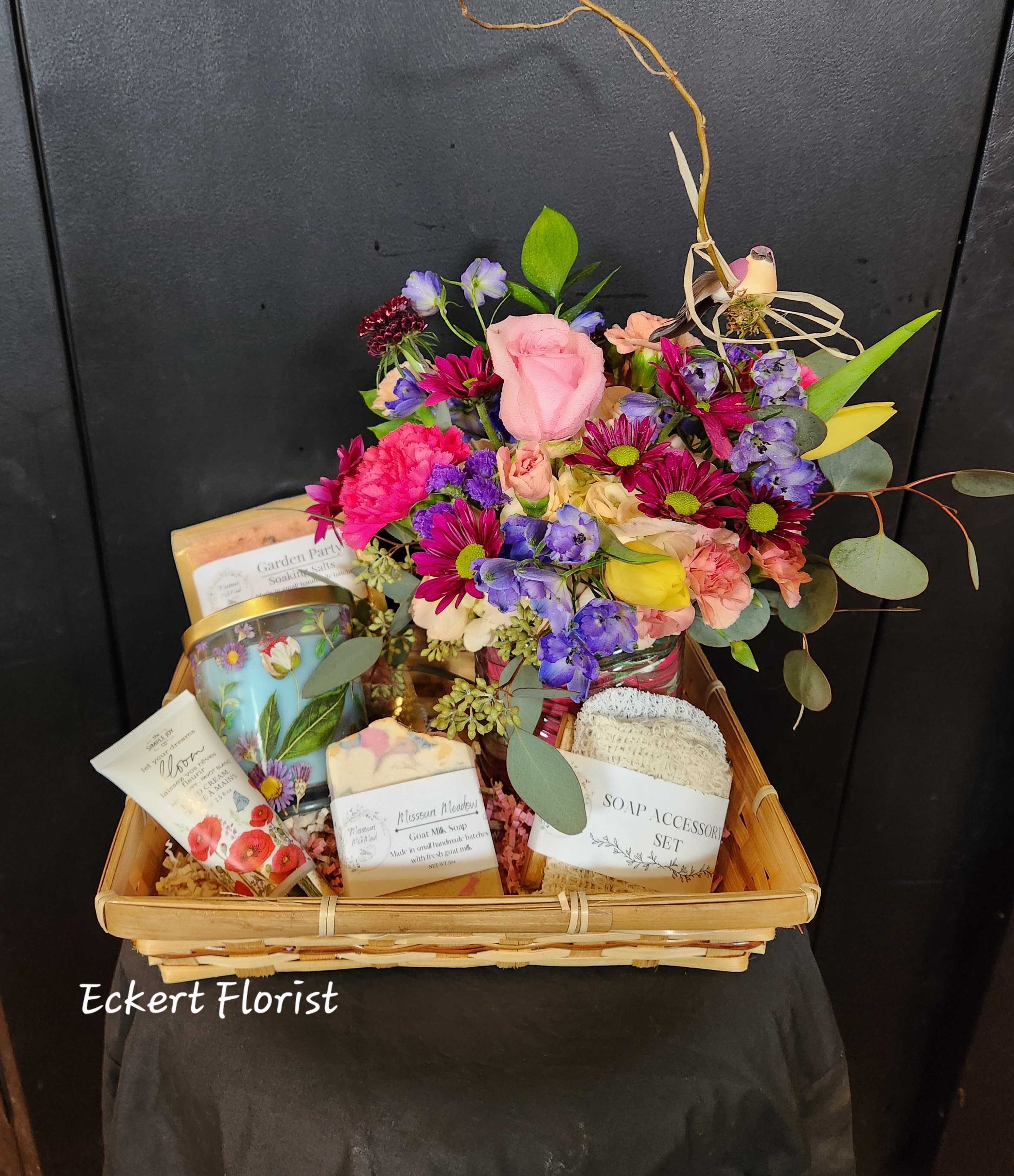 Gift basket with a mixed flower arrangement and bath products