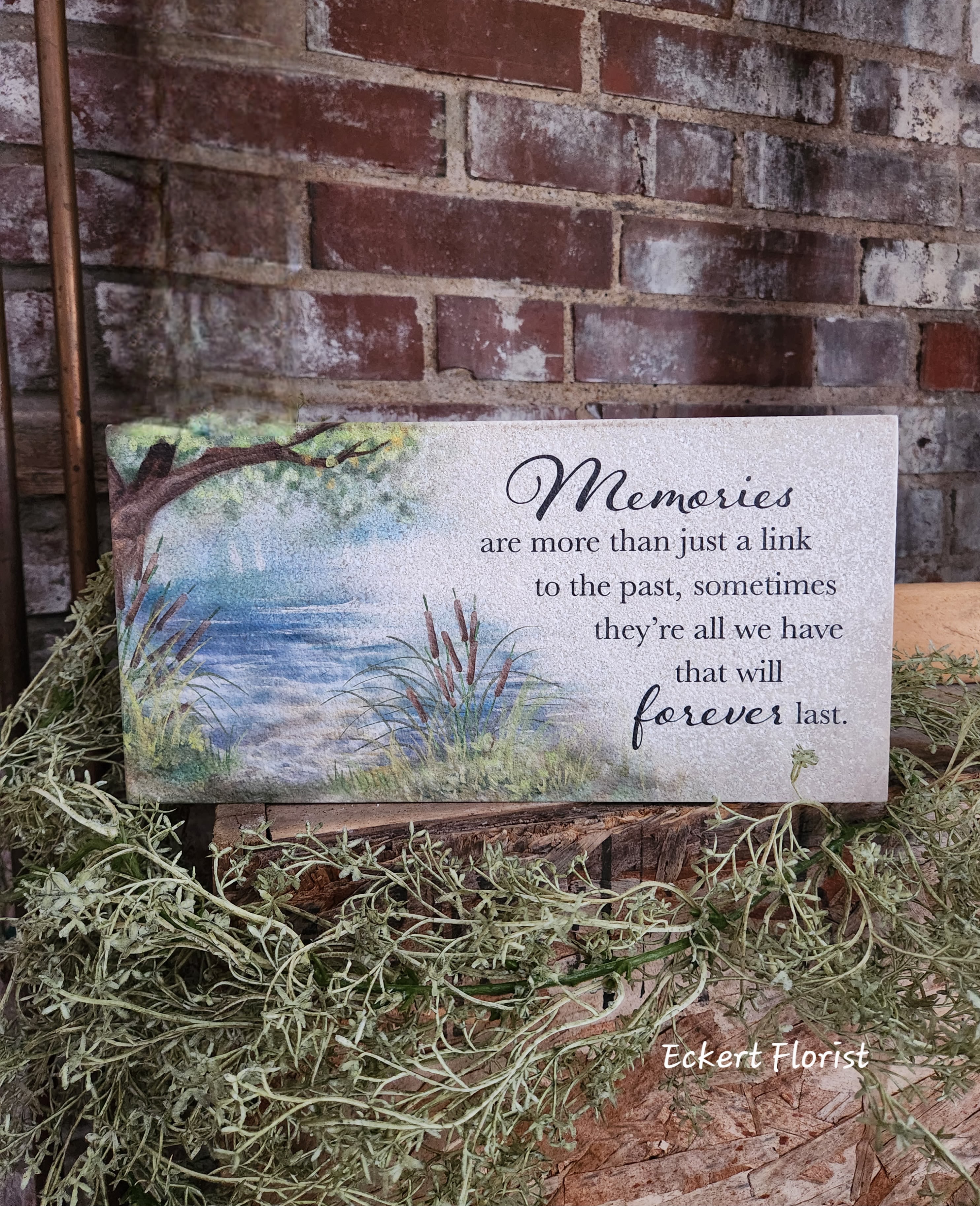 Memorial sign with a lake scene and quote on a rectangular plaque