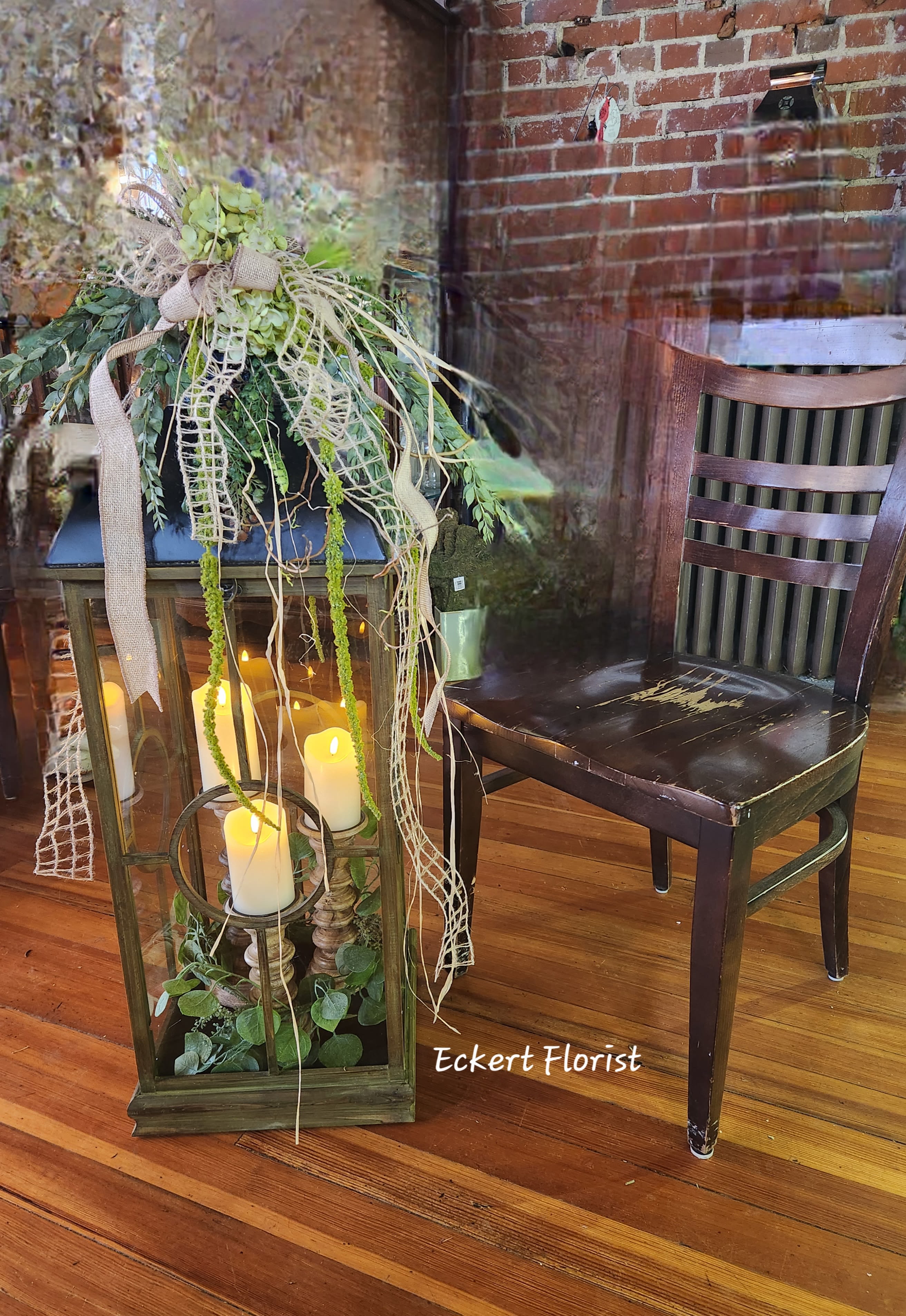 Lantern centerpiece with candles and trailing greenery on a wooden floor