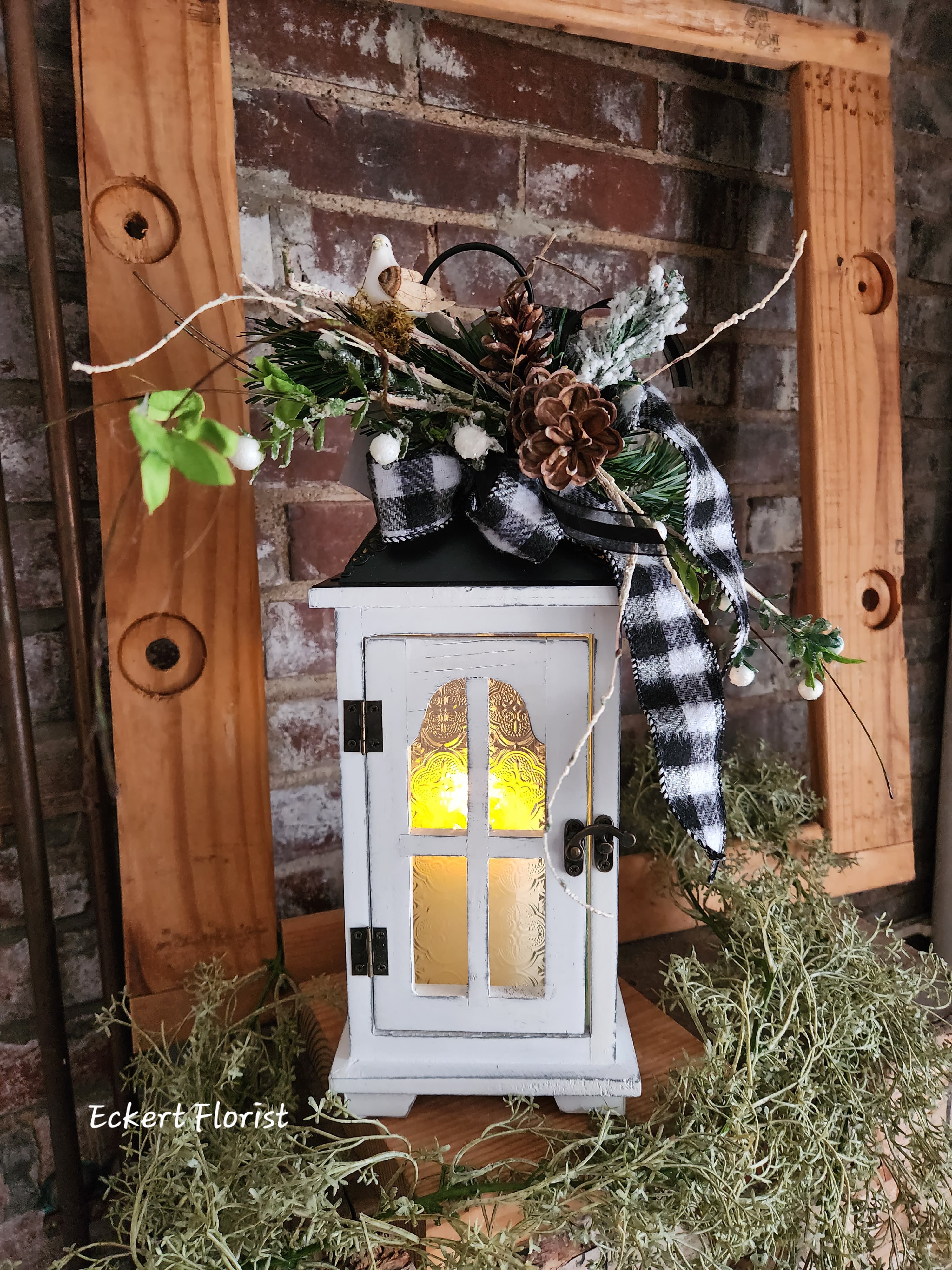 Decorative lantern with pinecones, plaid ribbon, and greenery