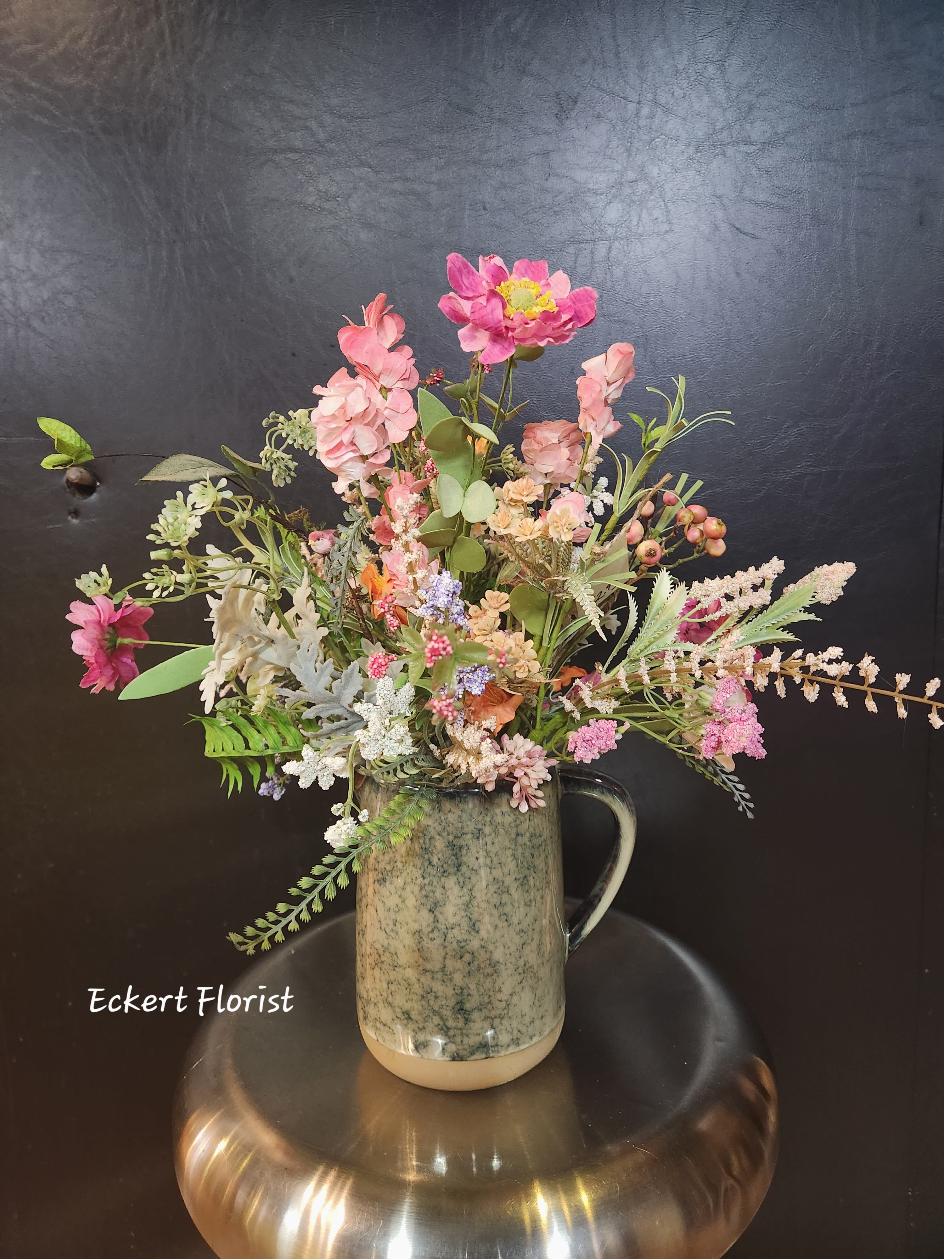 Mixed pink floral arrangement in a ceramic pitcher vase