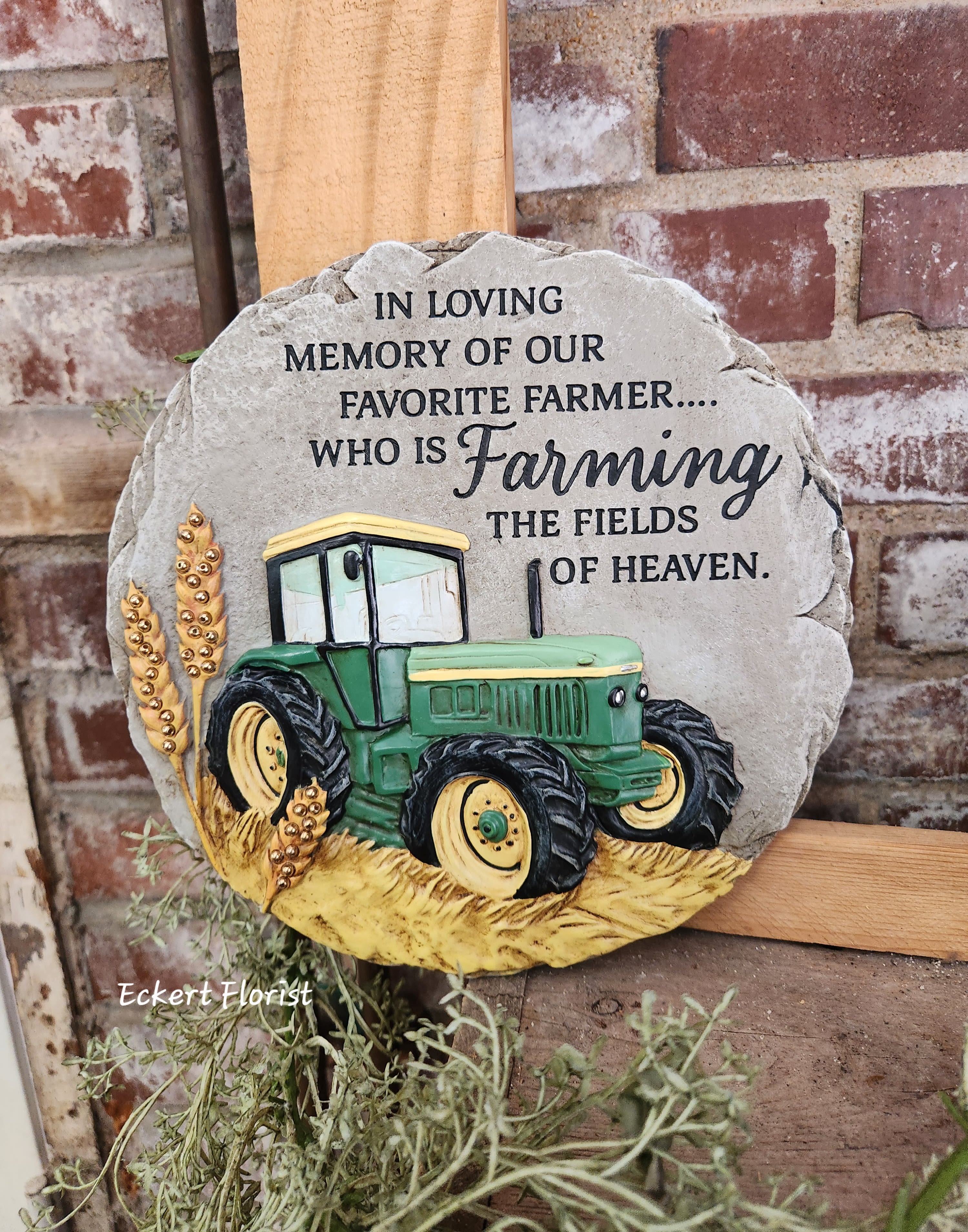 Eckert Florist's "Farming the Fields" Beadwork Garden Memorial Stone - Beadworks™ garden stones are cast in resin to emulate the look of real sandstone. Each piece is hand painted and includes beads for added detail. A keyhole hanger is cast in the back for hanging purposes or stone can be placed on the ground. This nice memorial keepsake may be sent to a funeral/memorial service or home. *May be added to a fresh arrangement or green plant. See Deluxe and/or Premium upgrades. *See Add-on Section for Display Easel 9.25" DIAMETER 