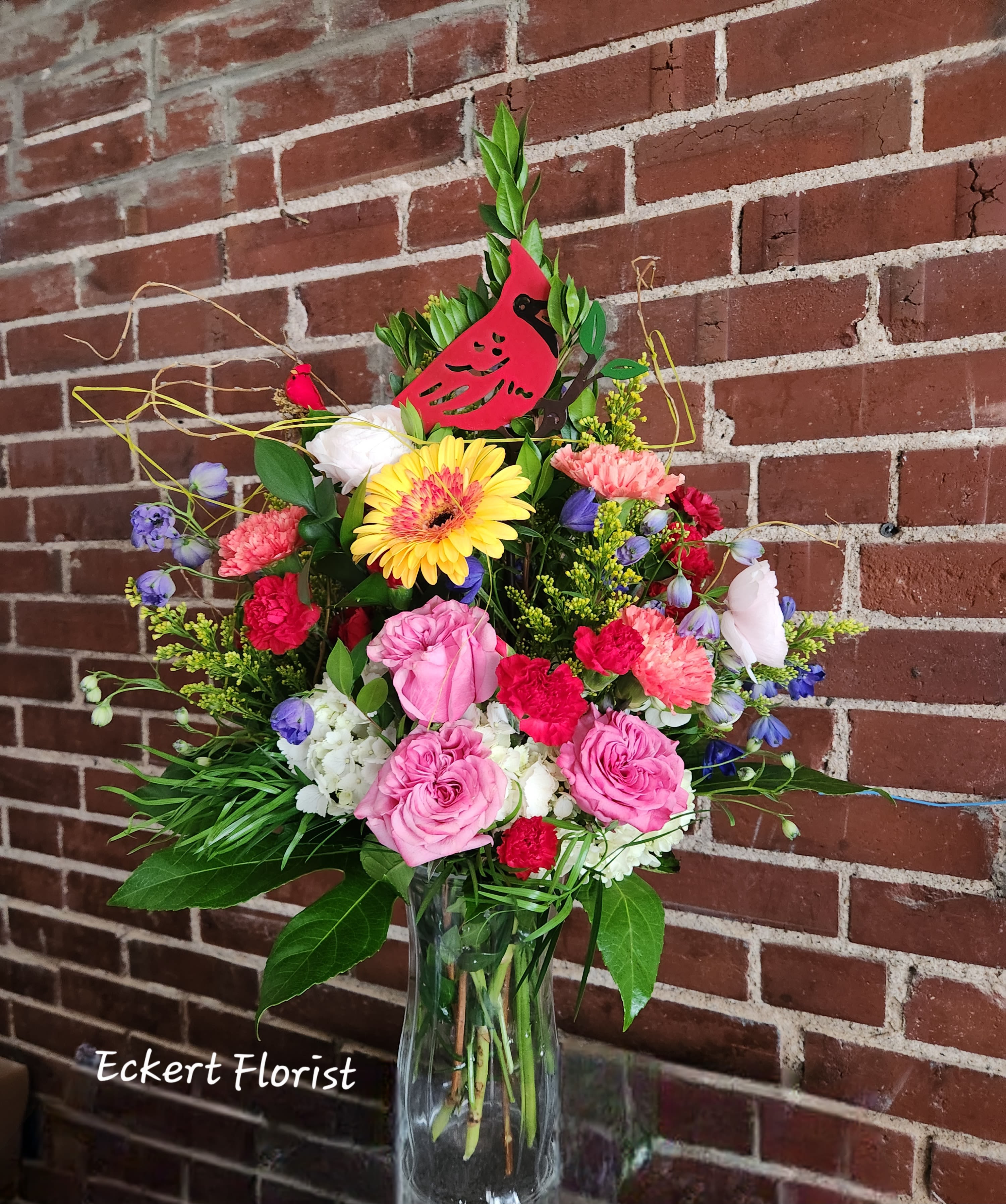 Eckert Florist's Cardinal Stake Bouquet - This mixed fresh vase arrangement arrives with a keepsake Cardinal bird garden stake. Fresh flower colors and varieties will vary. Metal stake measures 24" Tall x 7.25" Wide   