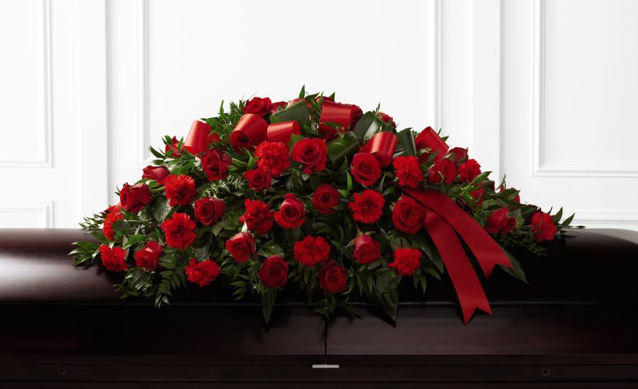 Red rose and carnation casket spray with a red ribbon