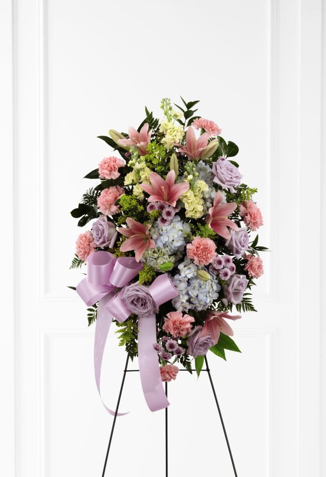 Standing floral spray with pink lilies, lavender roses, and pastel ribbons