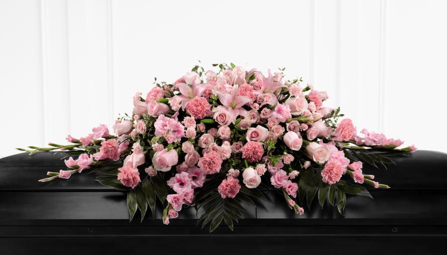 Pink floral casket spray with roses, carnations, and lilies