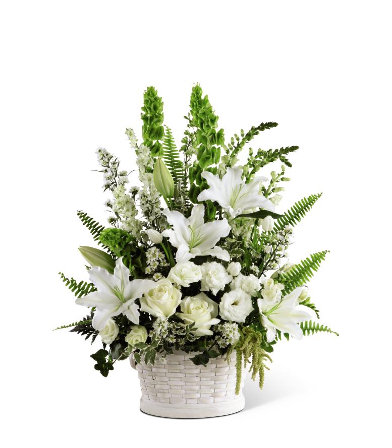 White lilies and roses with tall green bells of Ireland in a white woven basket