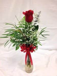 Red rose arrangement in a clear glass vase with a red ribbon