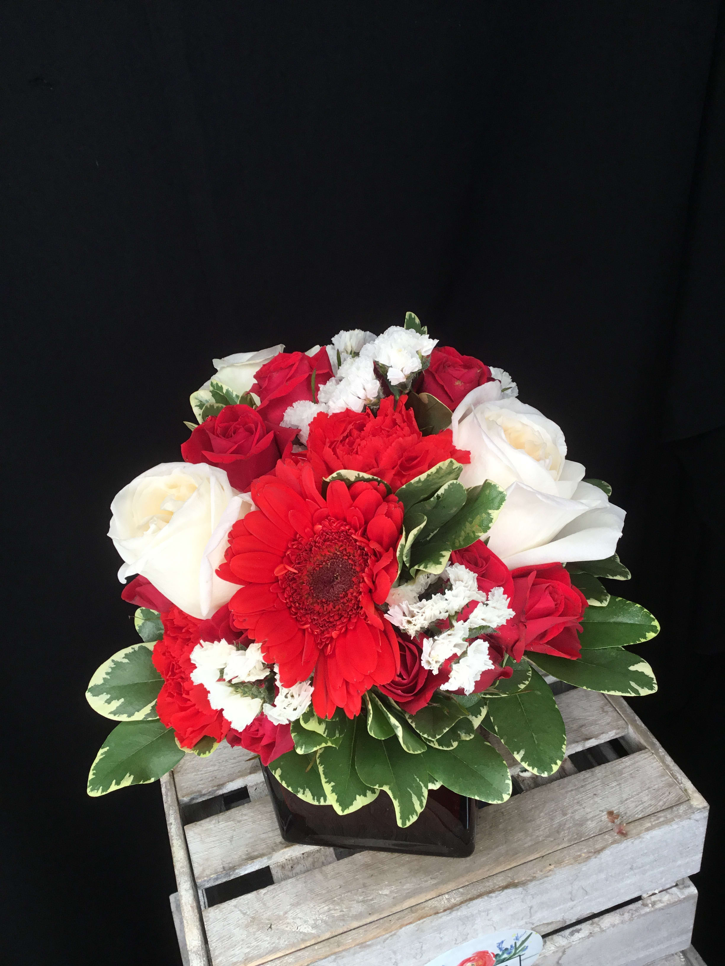 Red and white rose bouquet with a red gerbera daisy in a black vase