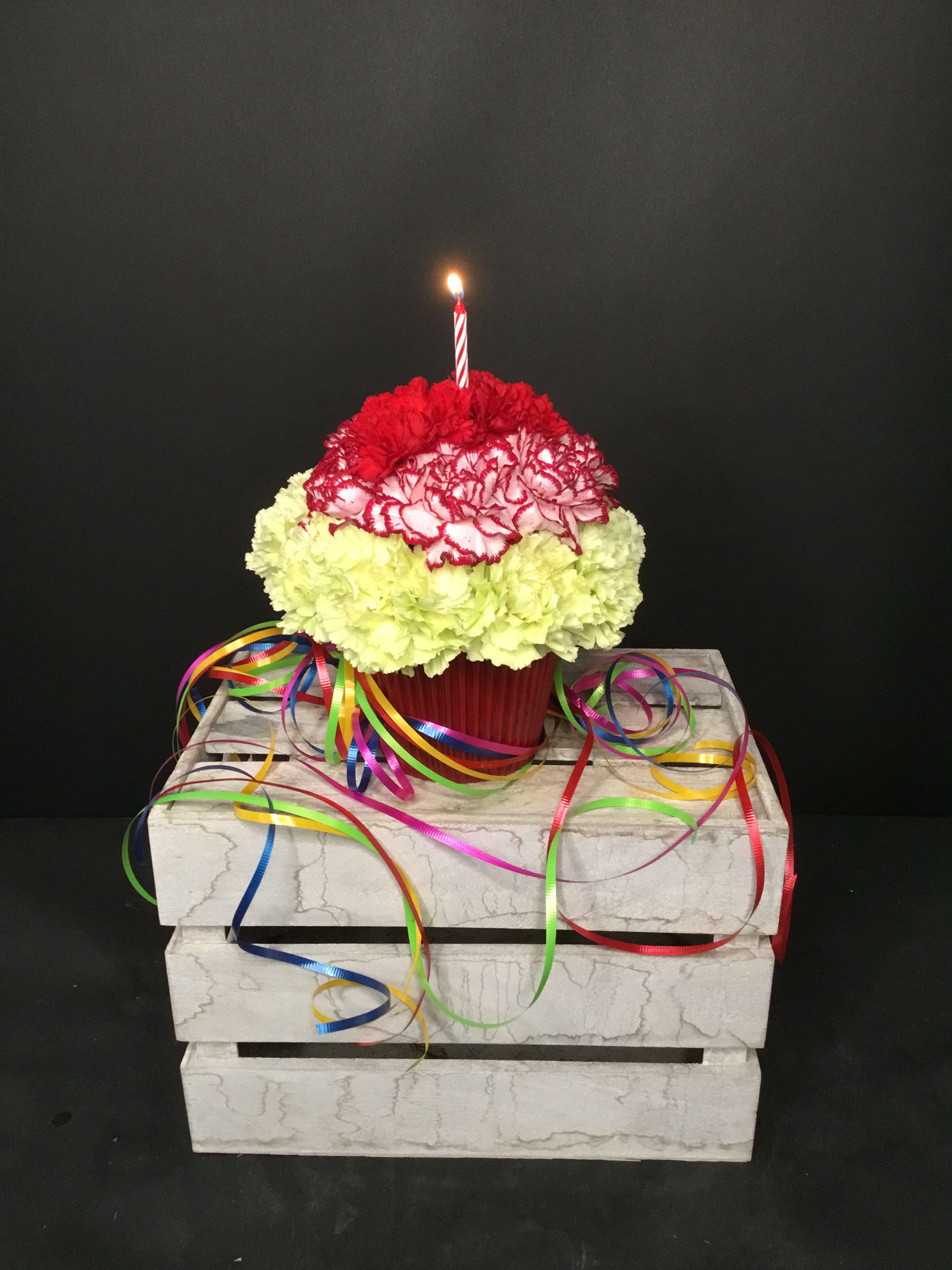 Carnation cupcake arrangement with a lit candle and colorful ribbons