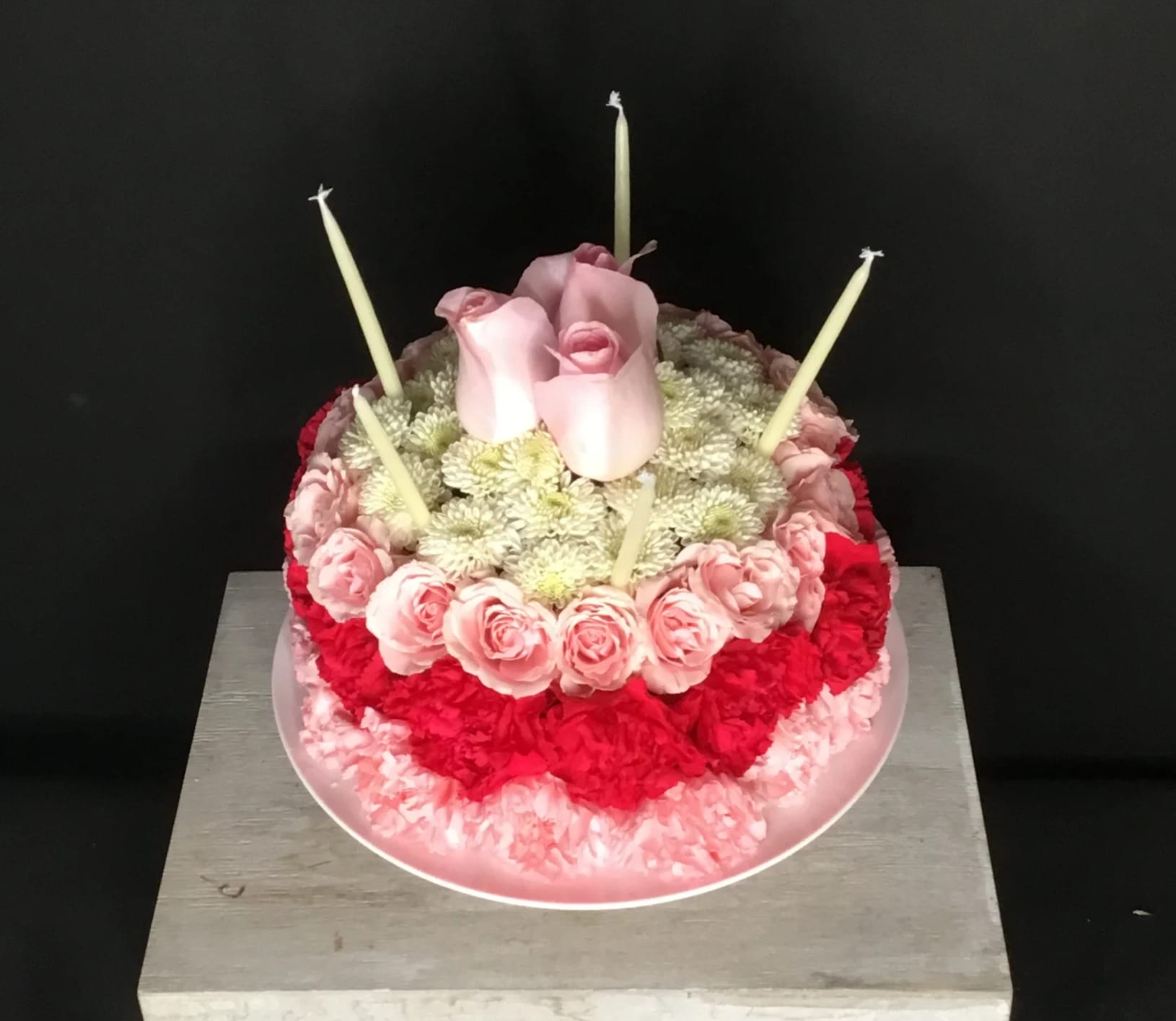 Blooming Birthday Cake (colors vary) - They'll never forget this incredible birthday surprise! Spray roses, pompons and mums create a fun-filled birthday greeting. Long lasting and quite unusual, this will make a lasting impression and bring some whimsy to your loved one's life! 