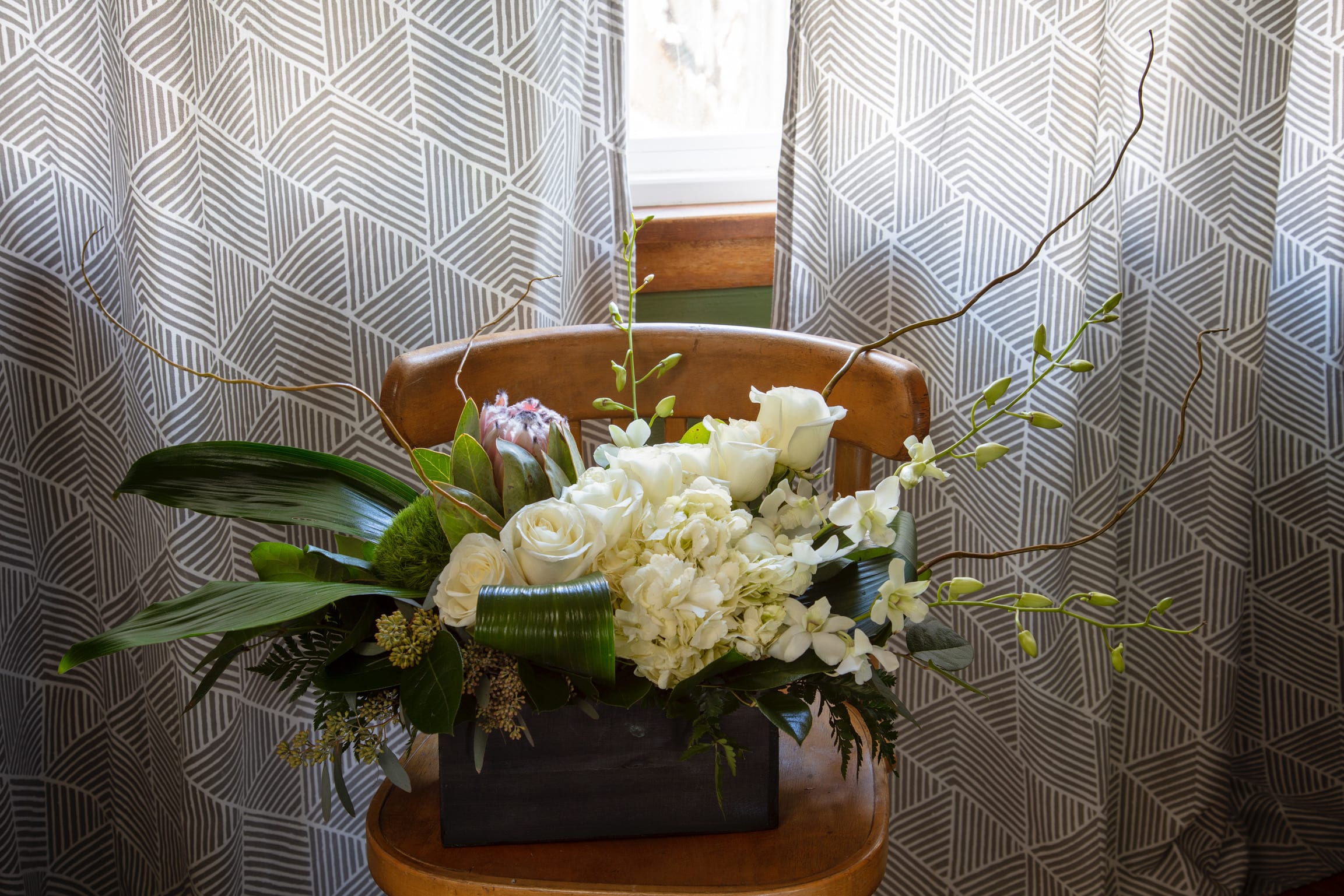 White floral arrangement in a dark rectangular container with long branches
