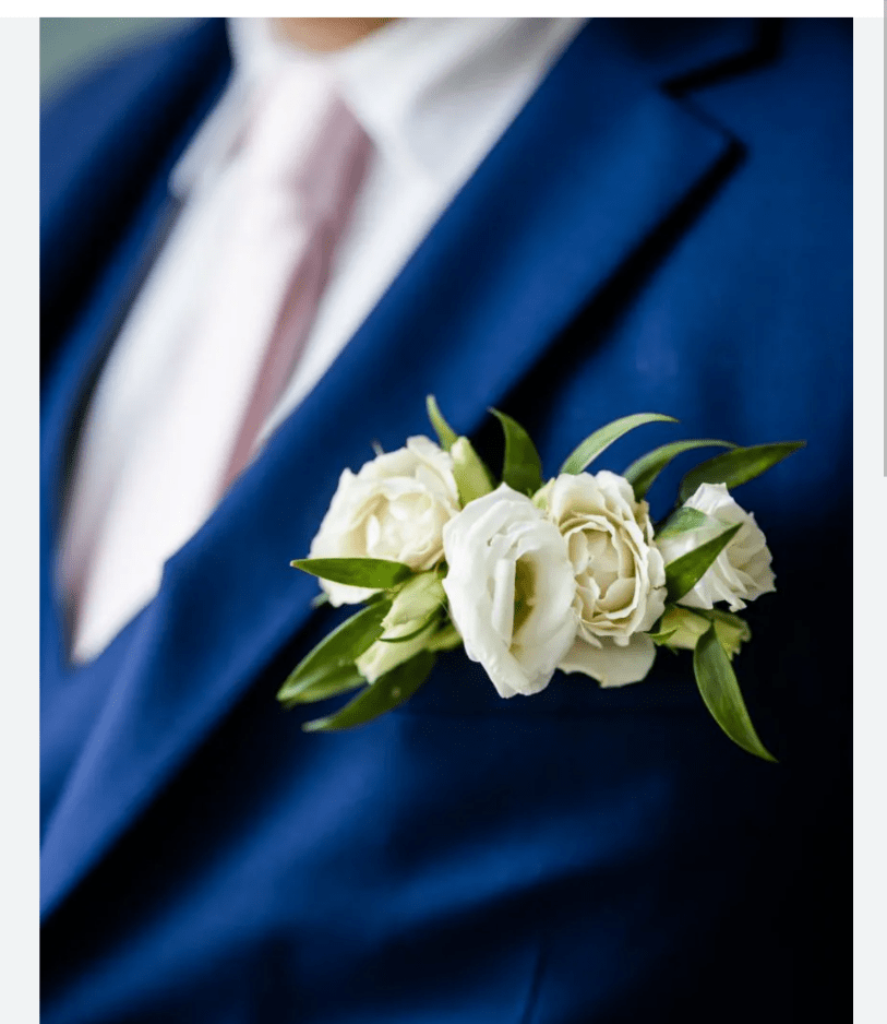White rose boutonniere pinned to a blue suit jacket