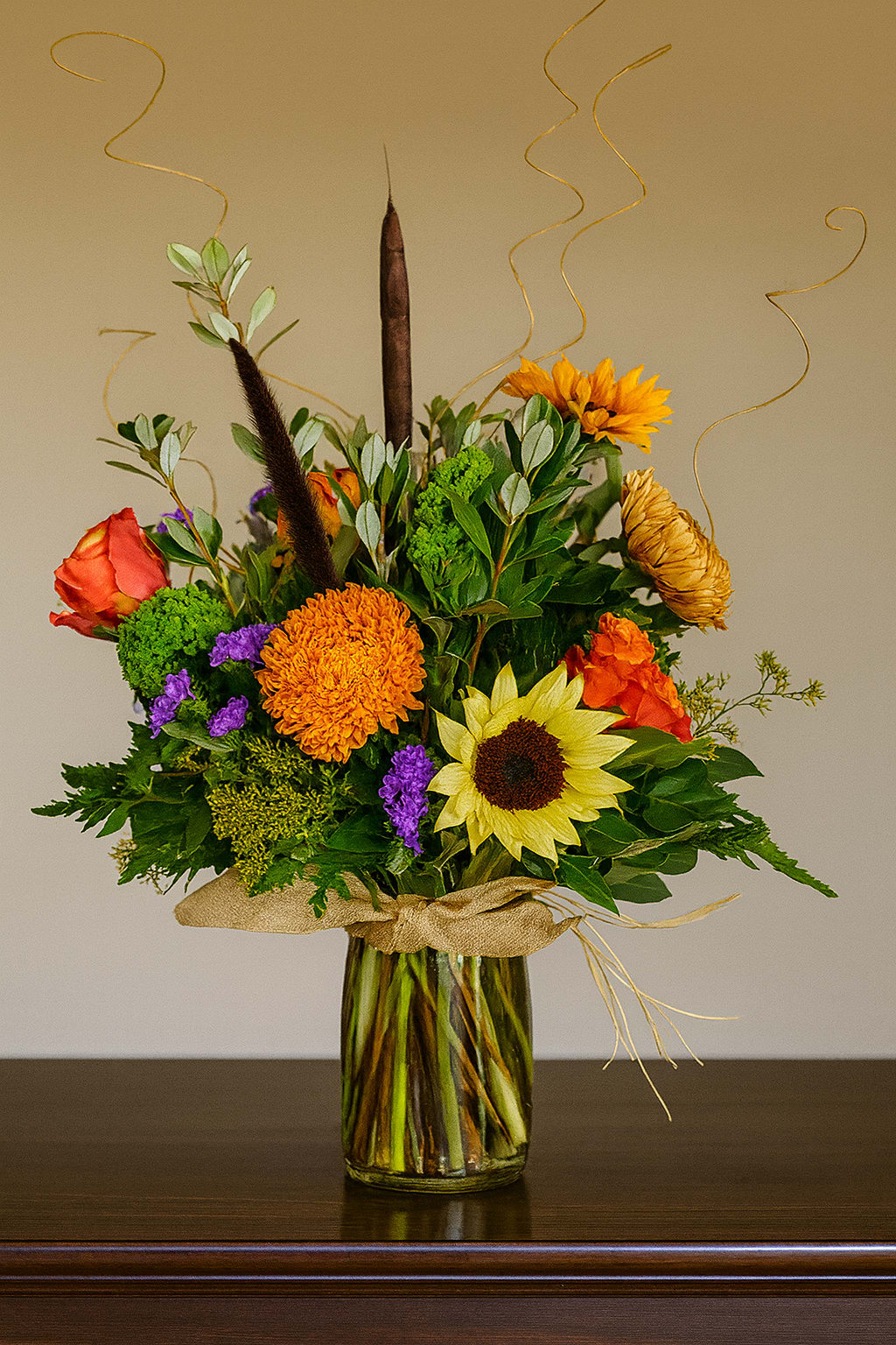 Mixed bouquet in a glass vase with sunflowers, roses, and orange blooms