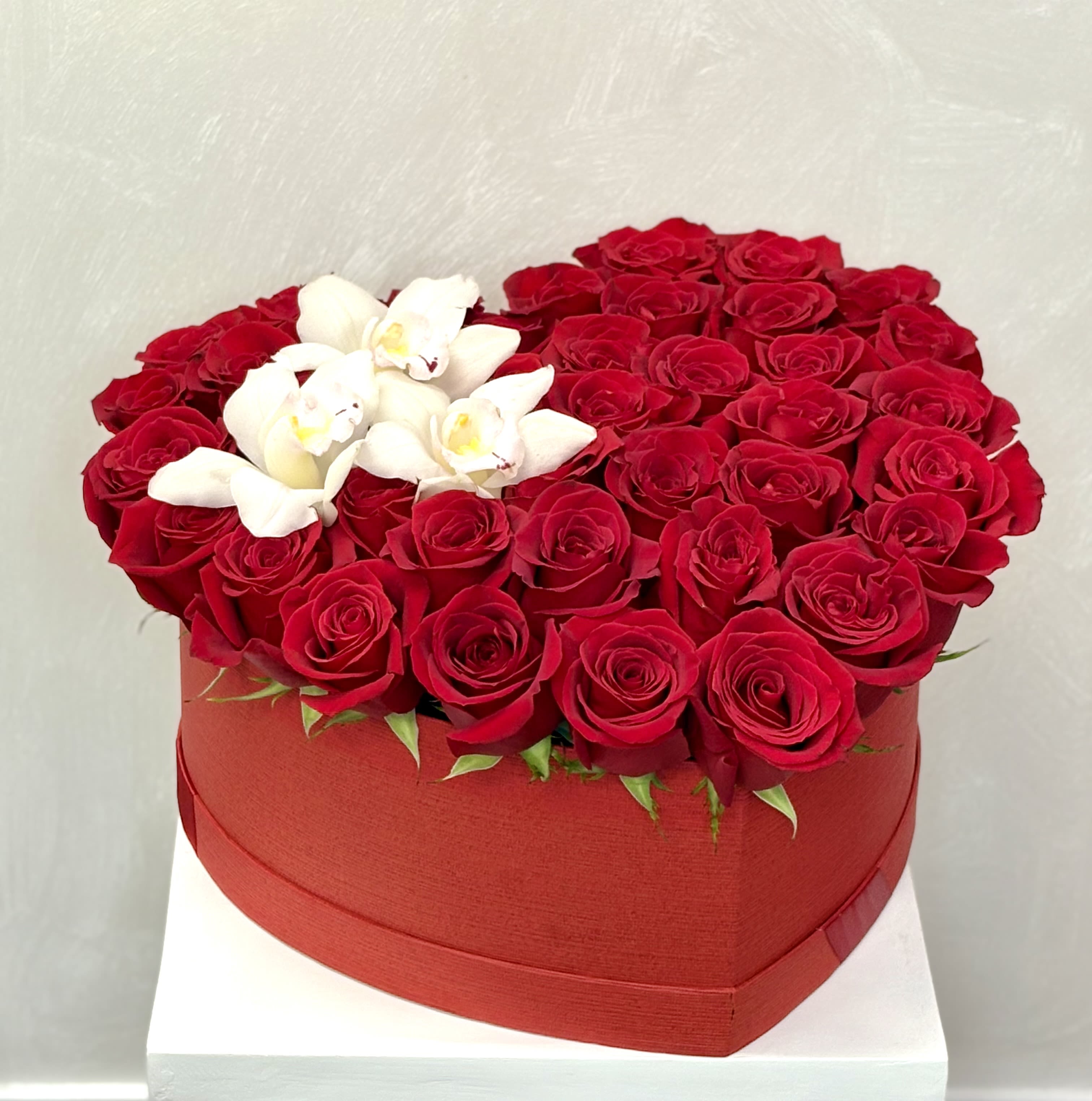 Heart-shaped box filled with red roses and white orchids